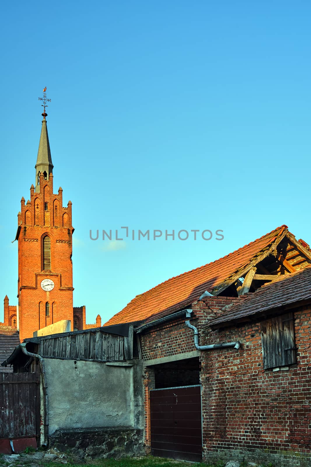 destroyed farm buildings and the tower of a historic gothic church in the village of Bledzew in Poland