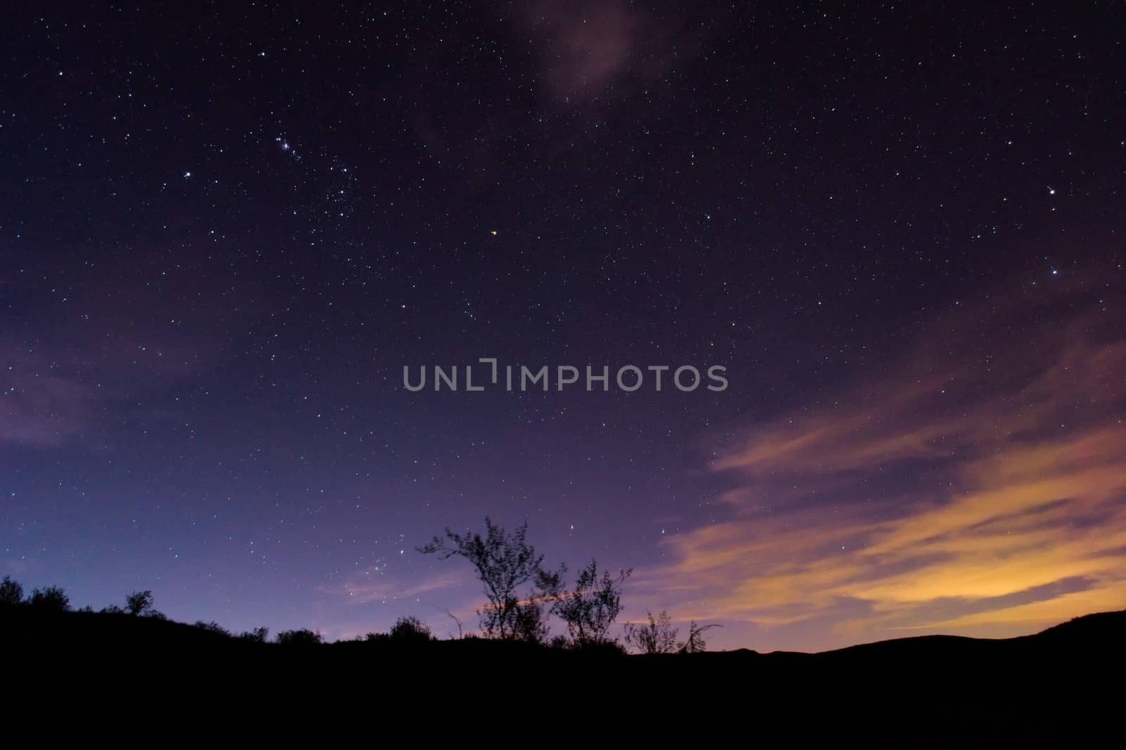 Night sky above the desert. Light pollution from the nearby city can be seen on the right side of the picture.