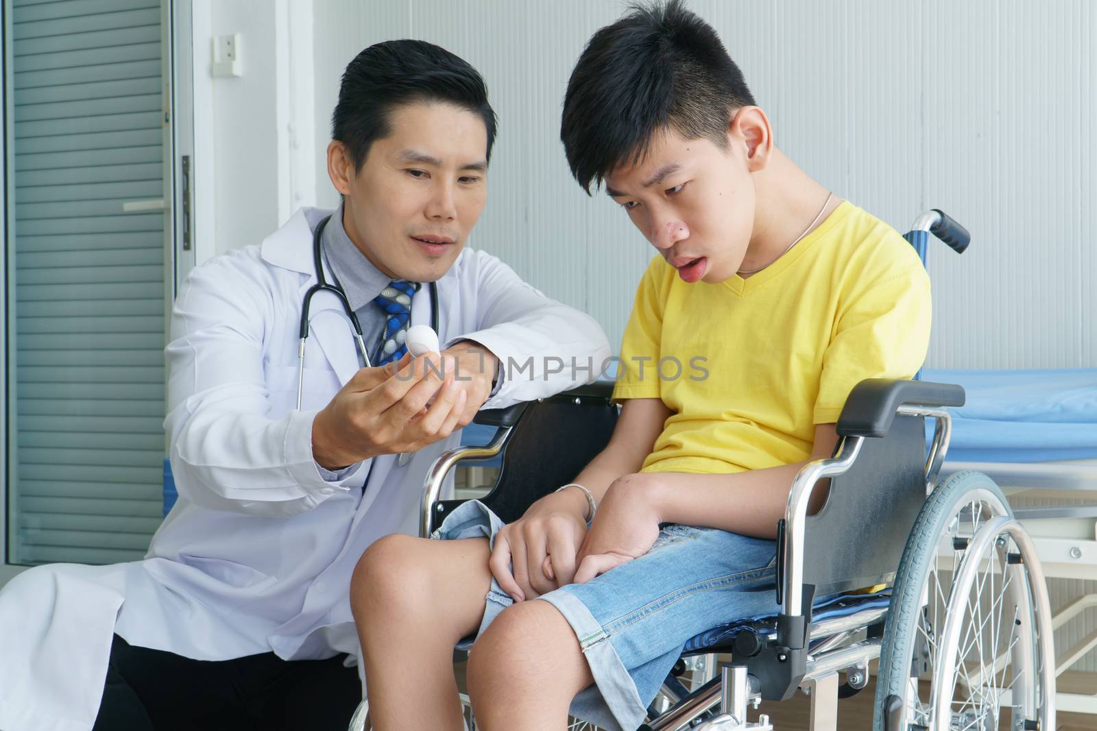 Asian doctors, adult men talking to patients with boy disabled in wheelchairs. Counseling and rehabilitation in disability in hospitals. Technology and modern medical science