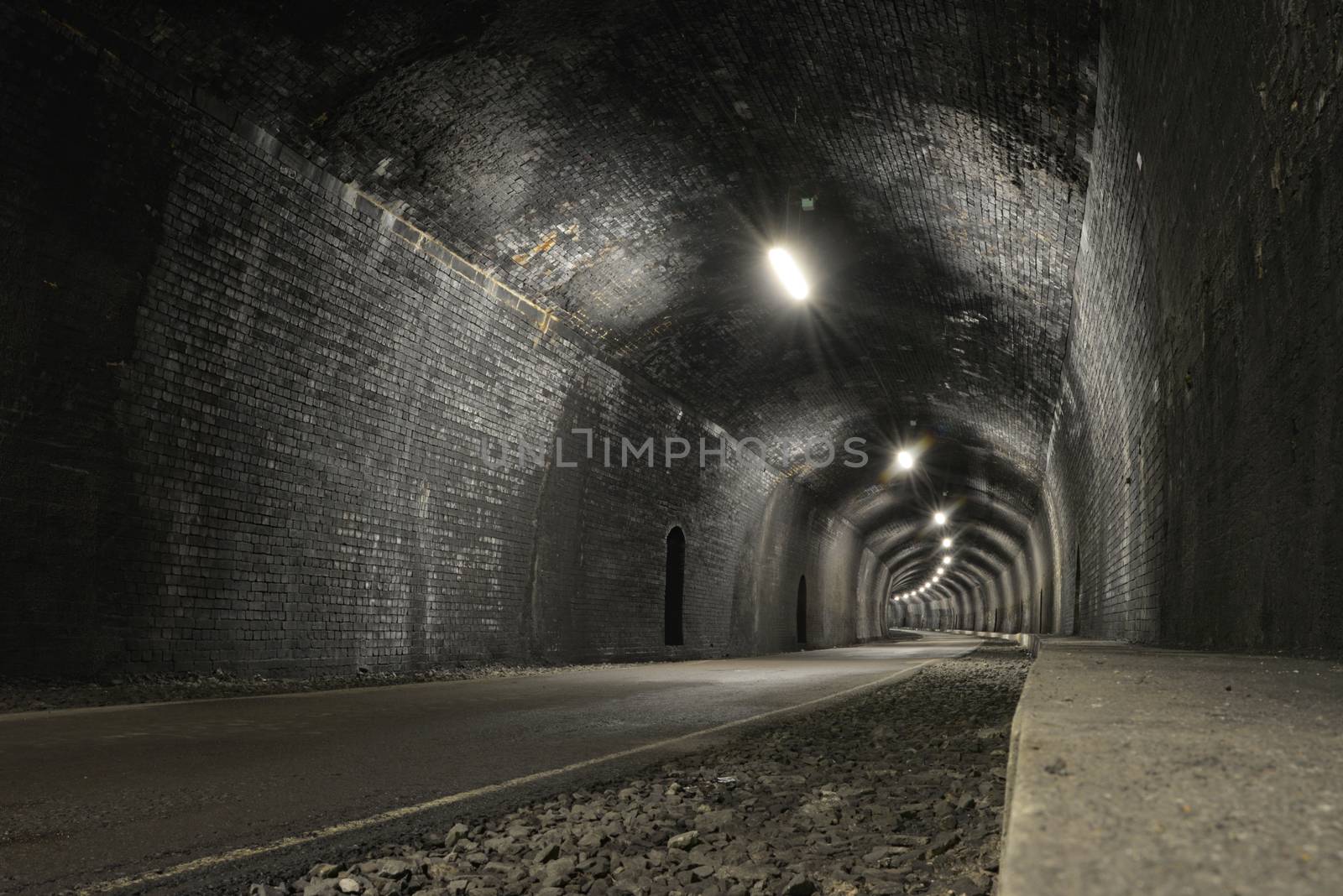 Monsal trail road passes through headstone tunnel, made of dark grey bricks, a low and wide angle image, blank and copy space. Old and rustic tunnel.