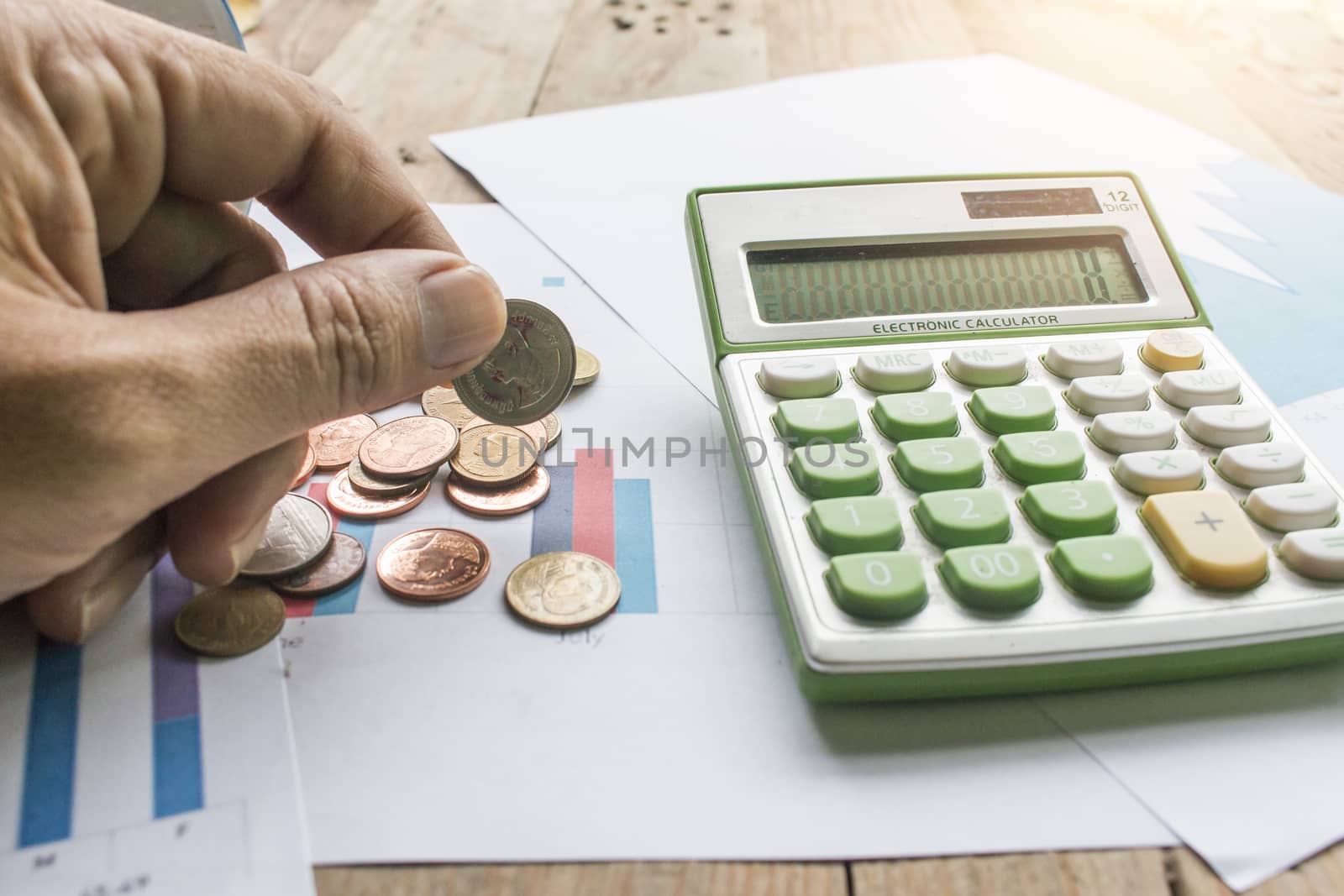 Hand holding coin with calculator on graph paper