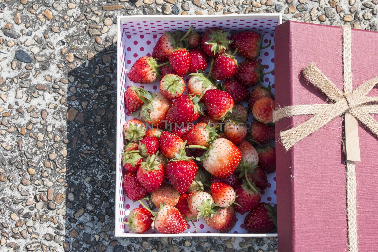 Fresh strawberry in gift box on stone background