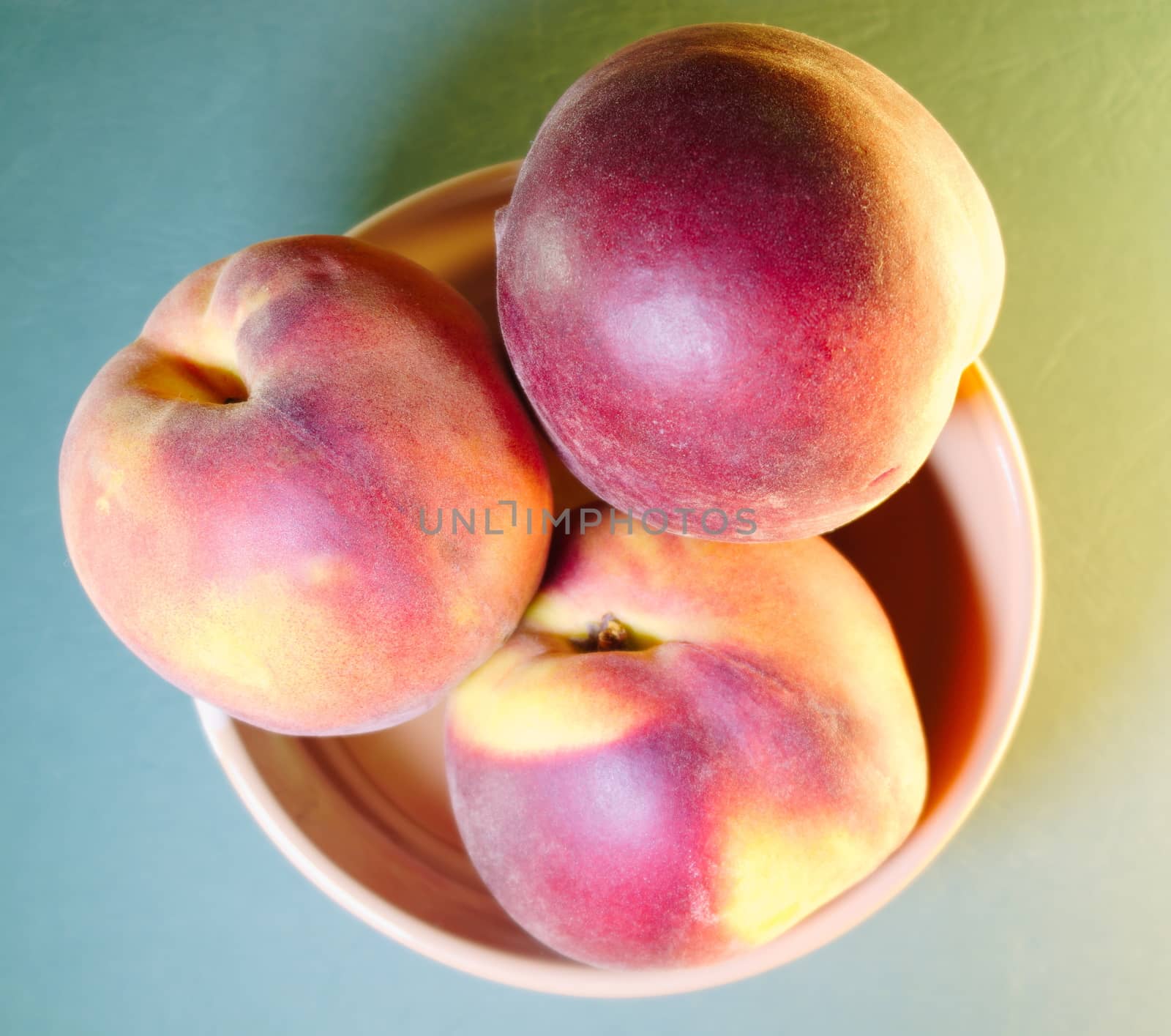 ripe peaches in a bowl on a light green background, top view