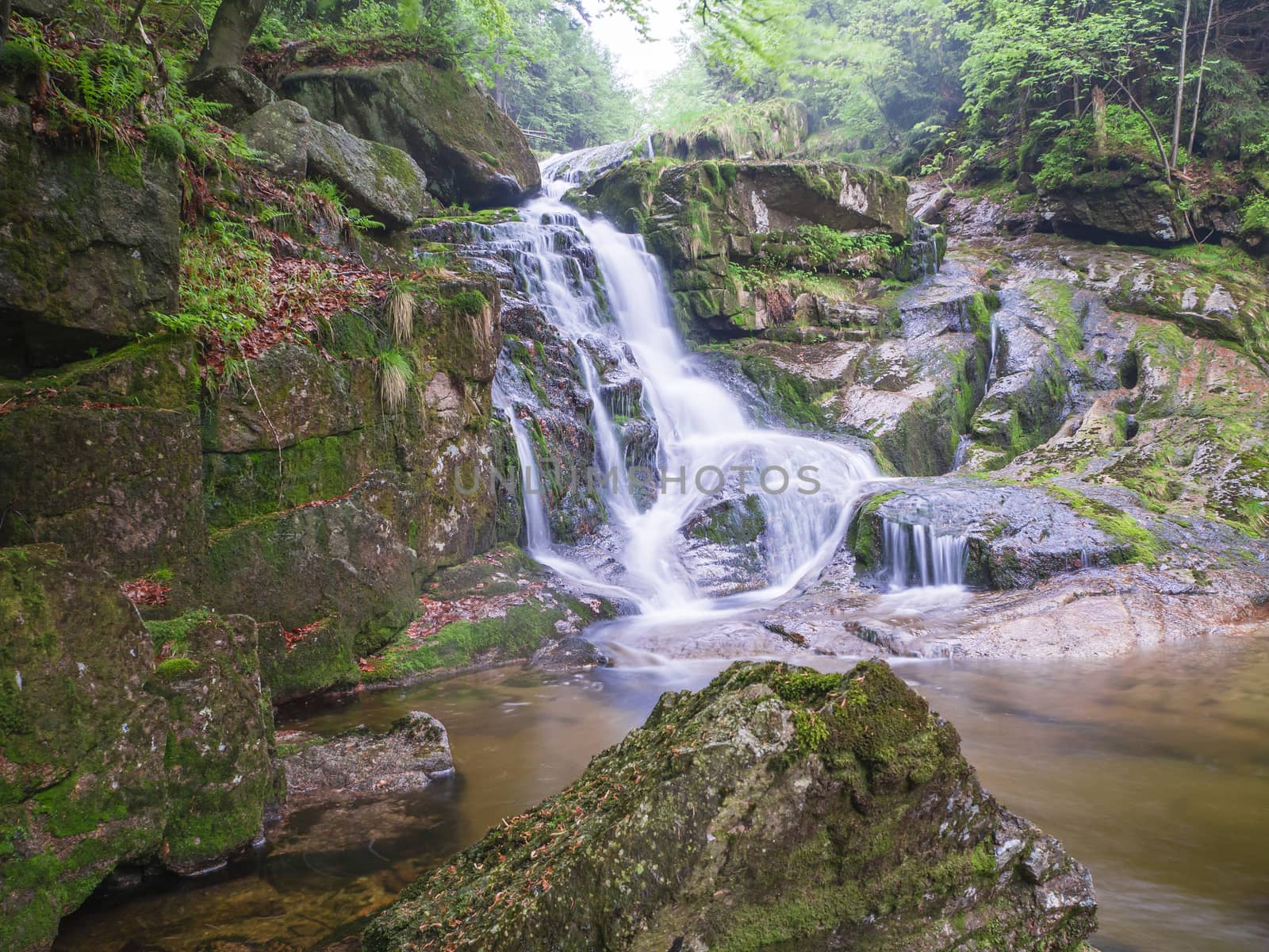 long exposure waterfall Poledni vodopad in Jizerske hory mountain forest on Cerny potok black creek in czech republic, green mossed stones and ferns