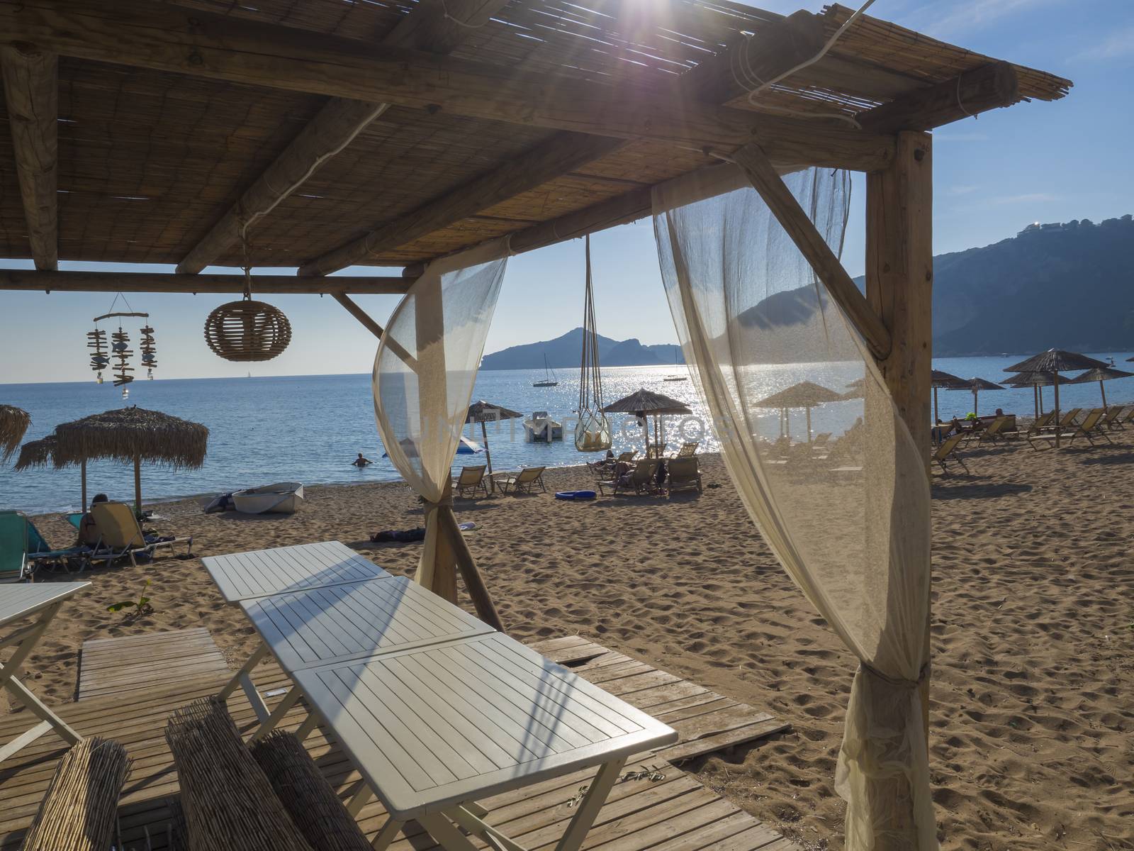 View on sand beach and sea at Agios Georgios Pagon at Corfu island, Greece Summer empty outdoor cafe at tropical island. Lens flare