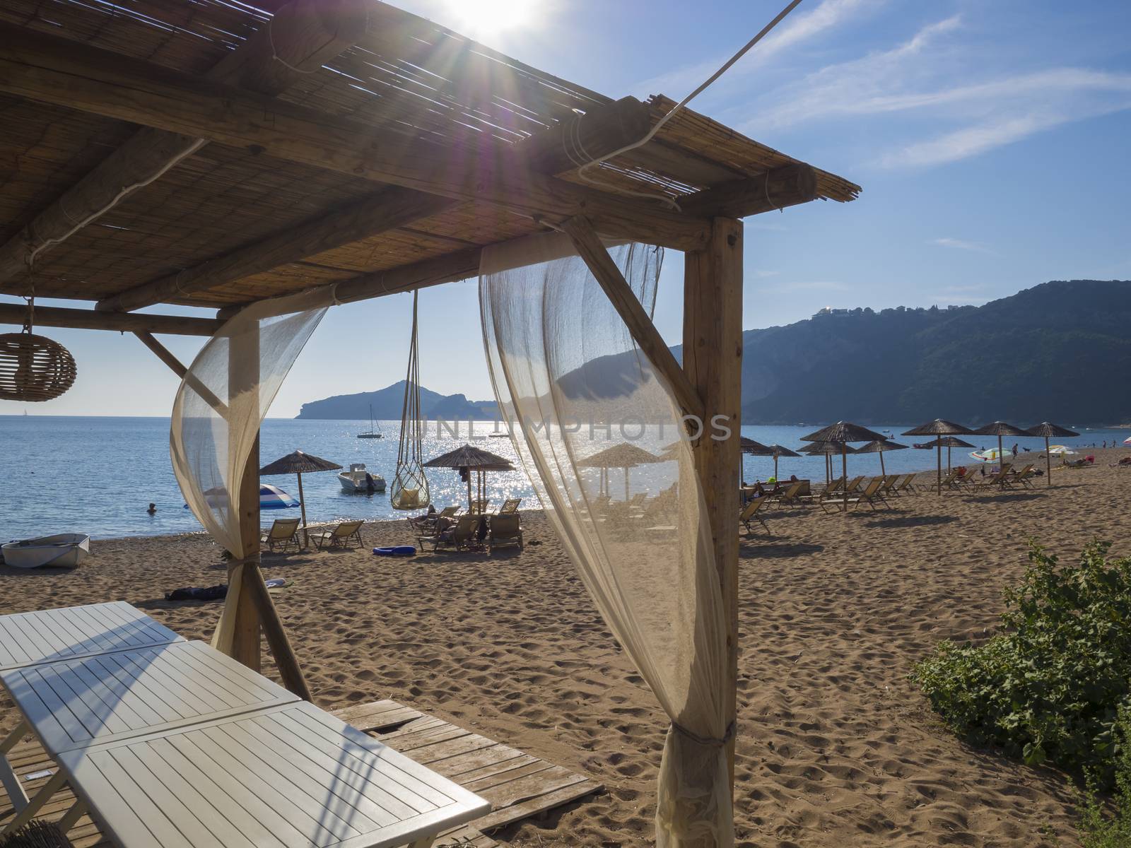 View on sand beach and sea at Agios Georgios Pagon at Corfu island, Greece Summer empty outdoor cafe at tropical island. Lens flare