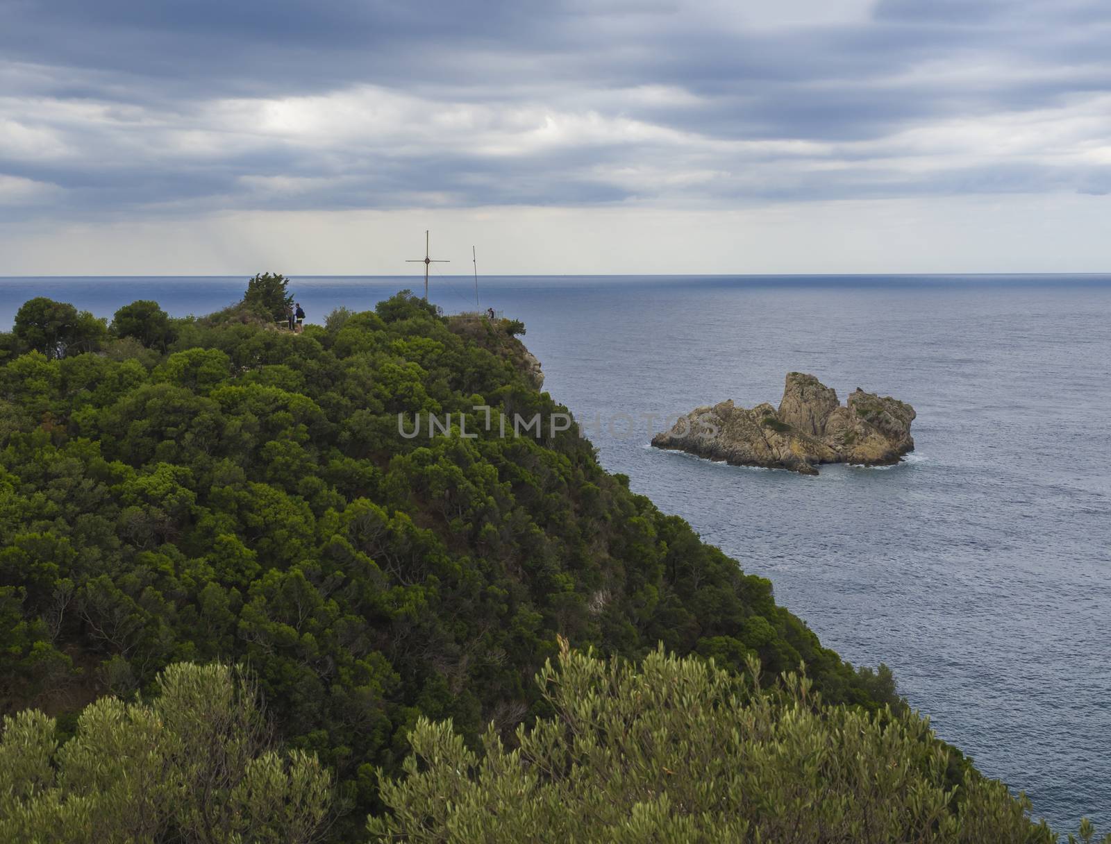 View point with cross and cllifs, trees and green hill at Paleokastritsa bay, summer cloudy sky, Corfu, Kerkyra, Greece by Henkeova