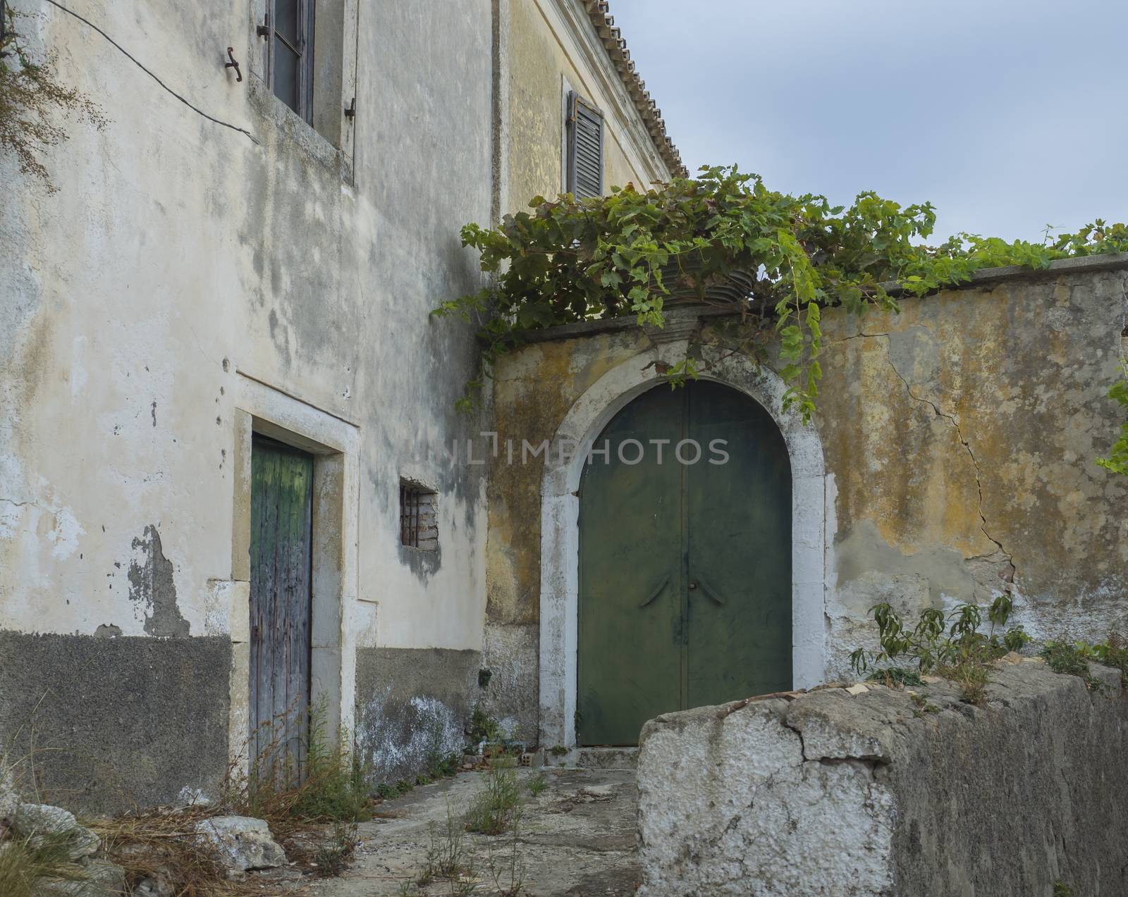 Shabby old house with flaking facade and green door at narrow street and stairs, vintage look, Corfu Greece by Henkeova