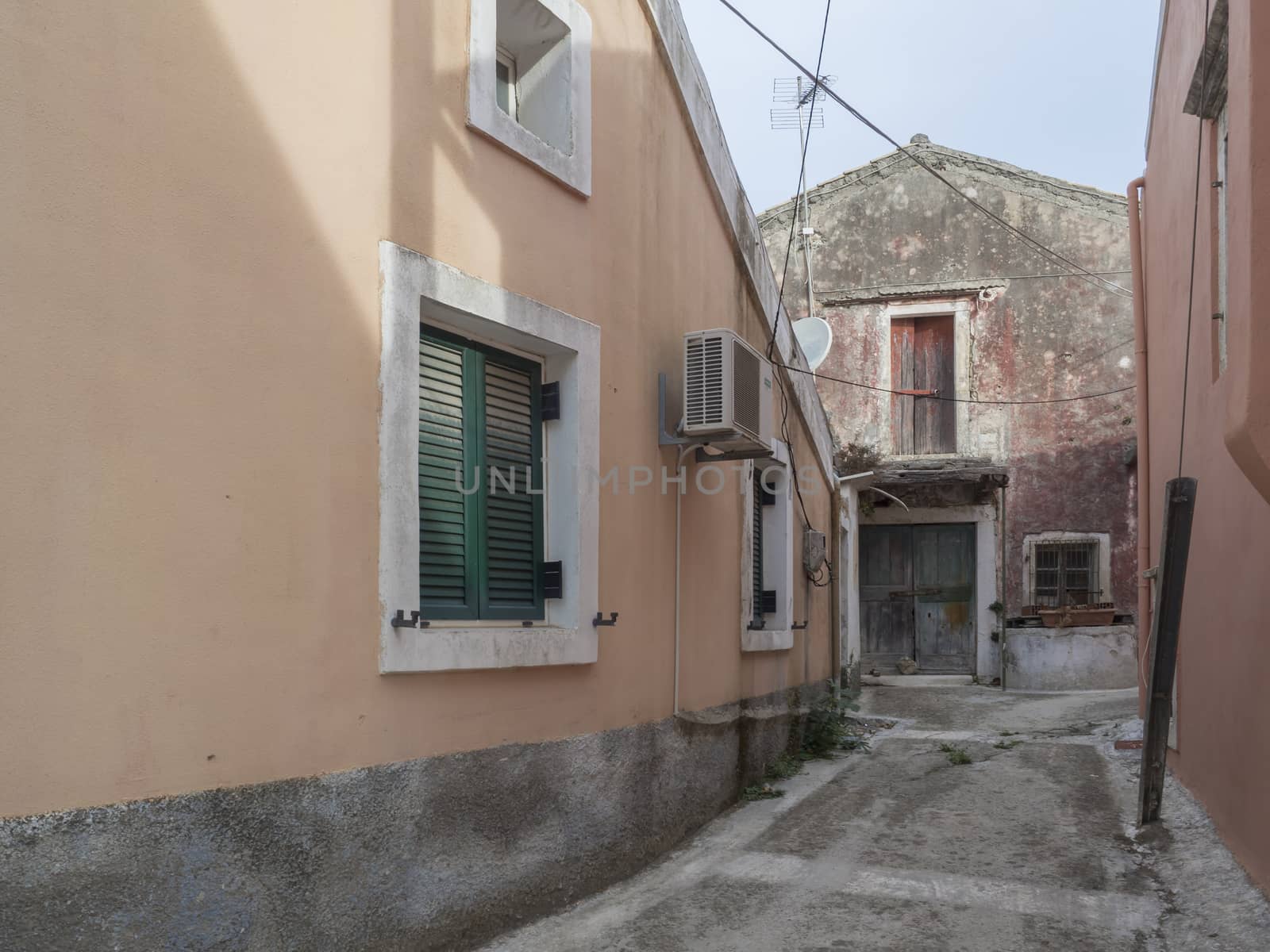 old narrow street with stone traditional houses and paving at village of Doukades on Corfu island Greece.