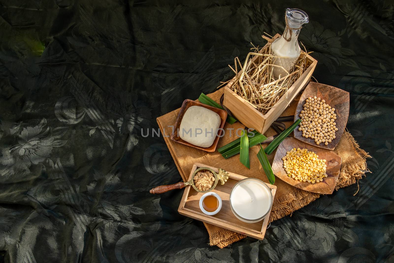 Soy products : A glass of Homemade soy milk and grains (soybeans) tofu Served with brown sugar and honey on sackcloth with lighting in the morning. Alternative milk concept, Selective focus, Copy space.