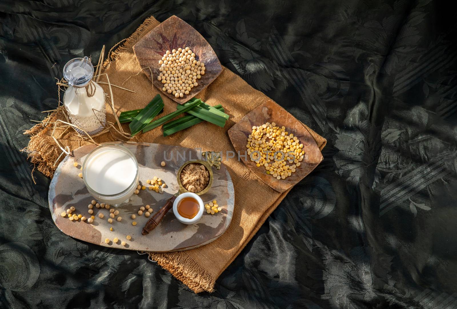 Soy products : A glass of Homemade soy milk and grains (soybeans) Served with brown sugar and honey on sackcloth with lighting in the morning. Alternative milk concept, Selective focus, Copy space.