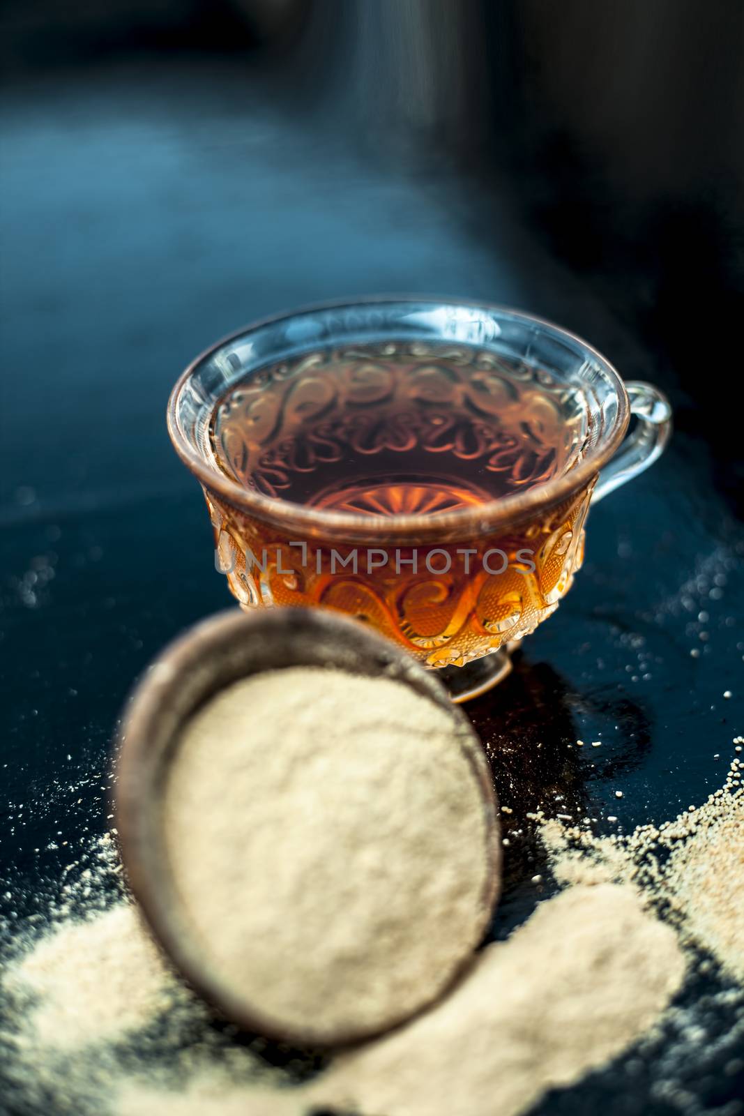 Clay bowl on wooden surface full of Poppy seeds or khus or opium poppy or bread seed poppy with its extracted herbal and organic plus beneficial detoxifying drink or tea in a transparent glass cup.