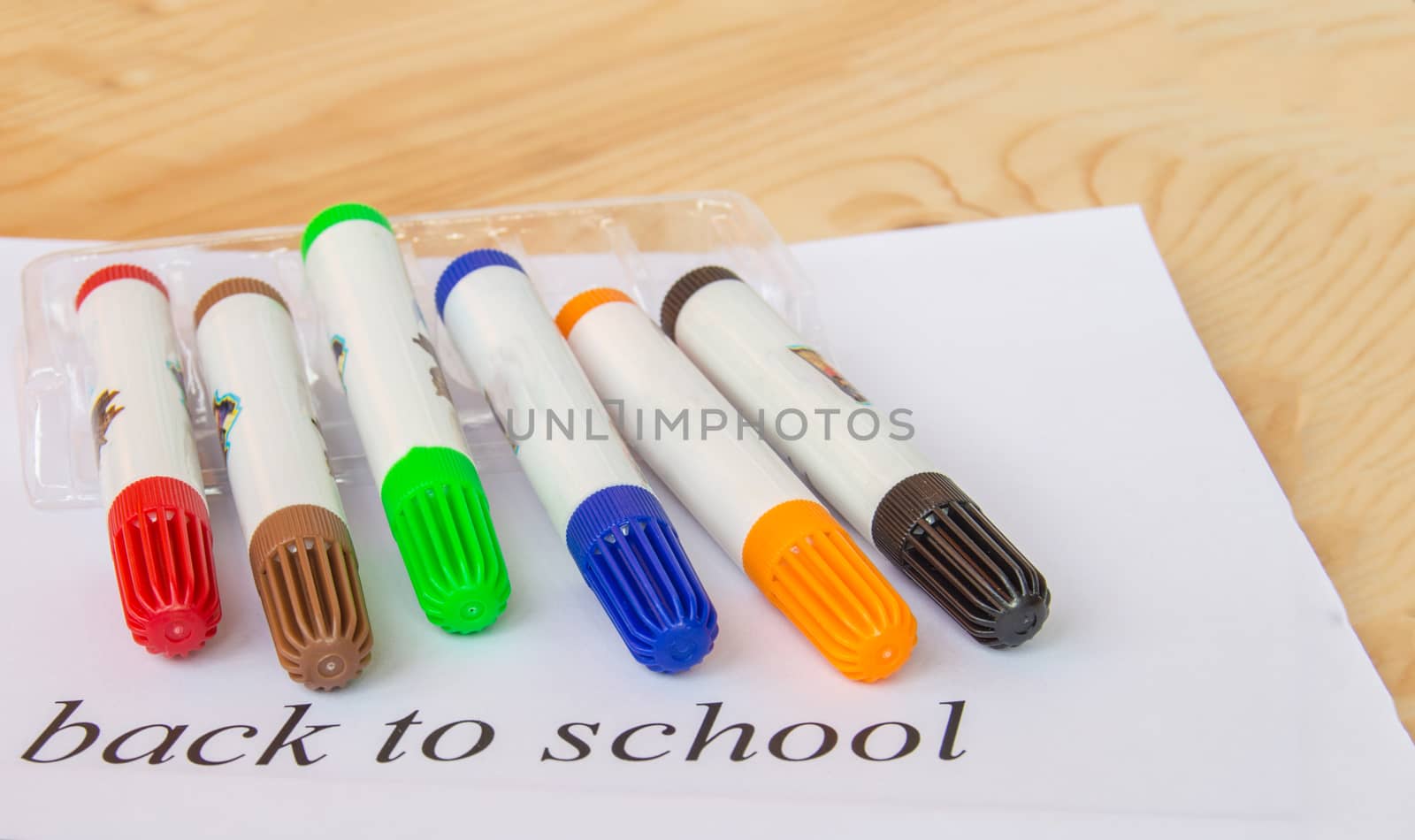 A white sheet of paper with the inscription back to school, colorful markers for drawing, the concept of education.