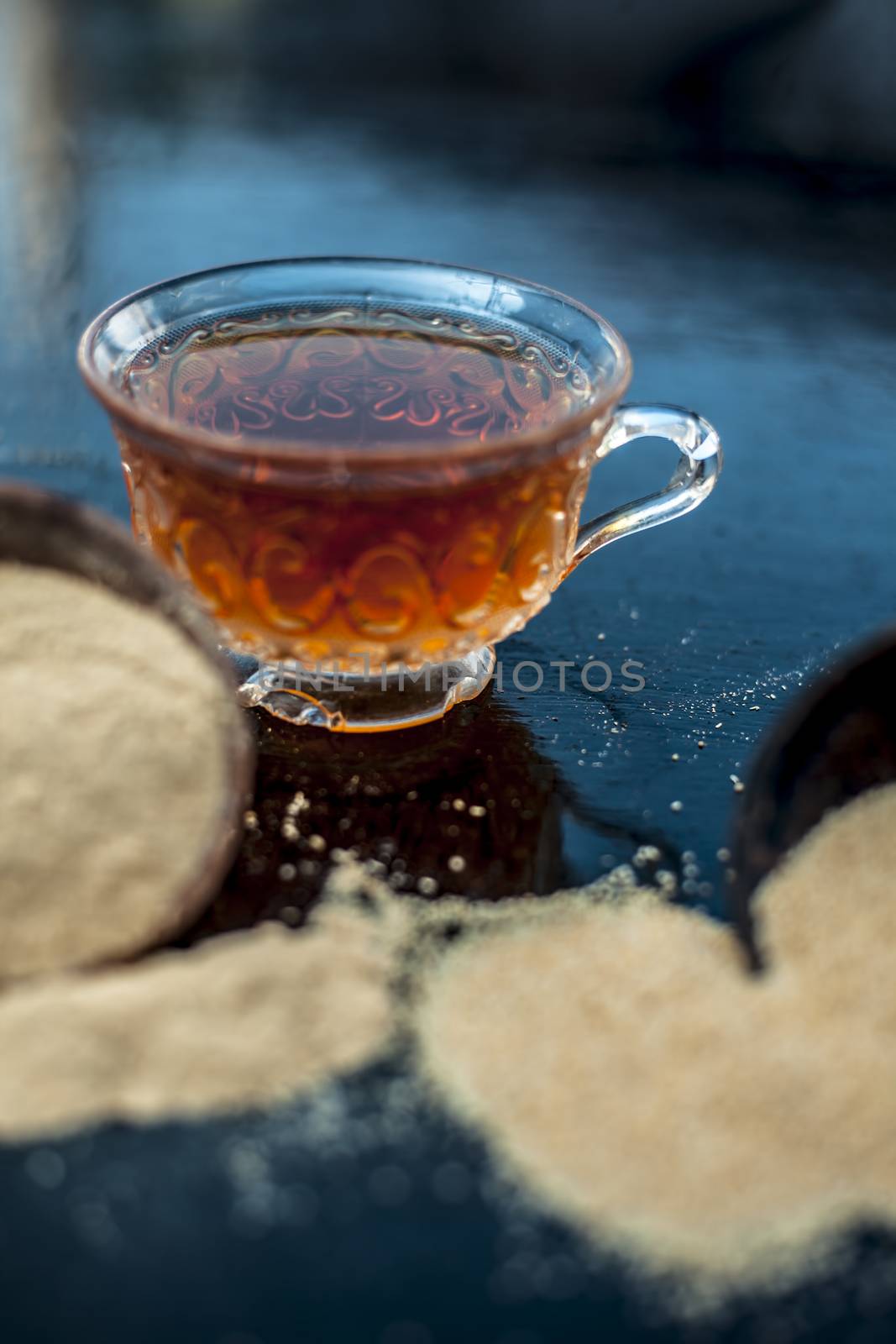 Clay bowl on wooden surface full of Poppy seeds or khus or opium poppy or bread seed poppy with its extracted herbal and organic plus beneficial detoxifying drink or tea in a transparent glass cup.