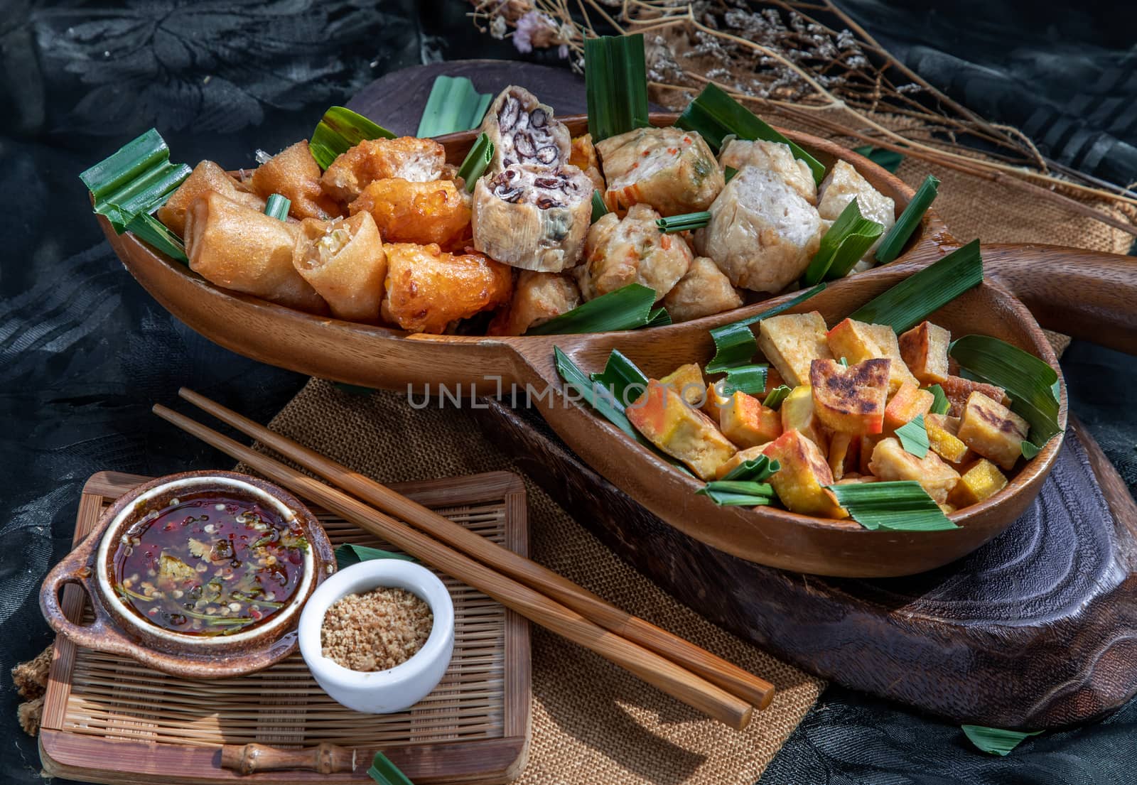 Many vegetarian food : Fried taro rolls (Taro Guangjian) and Deep fried spring rolls, Fried tofu, Fried radish, Fried taro and black beans (Zhu jiao quan or Fried taro cakes) Served with spicy sweet sauce and roasted crushed peanuts with wooden chopsticks on wooden plate. Selective focus.