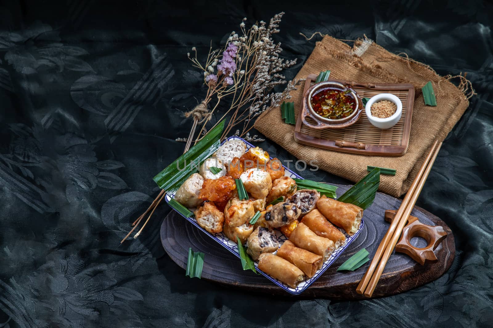 Many vegetarian food : Fried taro rolls (Taro Guangjian) and Deep fried spring rolls, Fried tofu, Fried radish, Fried taro and black beans (Zhu jiao quan or Fried taro cakes) Served with spicy sweet sauce and roasted crushed peanuts with wooden chopsticks on Ceramic dishes. Selective focus.
