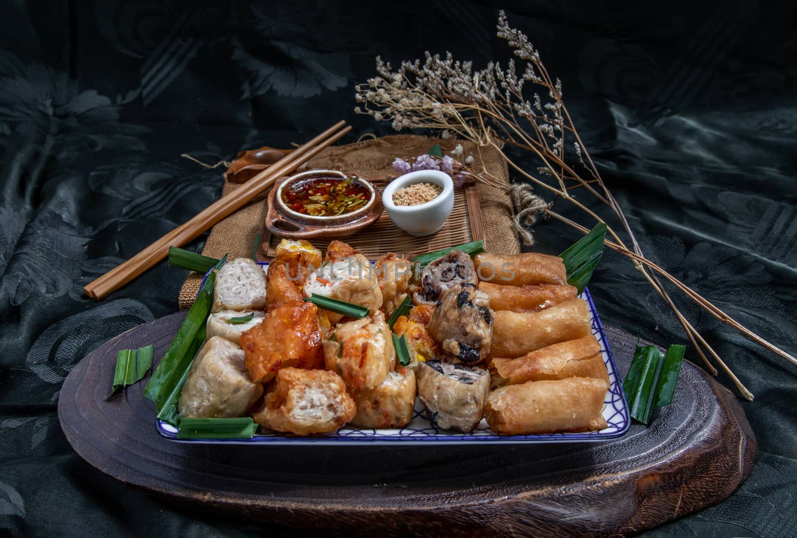 Many vegetarian food : Fried taro rolls (Taro Guangjian) and Deep fried spring rolls, Fried tofu, Fried radish, Fried taro and black beans (Zhu jiao quan or Fried taro cakes) Served with spicy sweet sauce and roasted crushed peanuts with wooden chopsticks on Ceramic dishes. Selective focus.