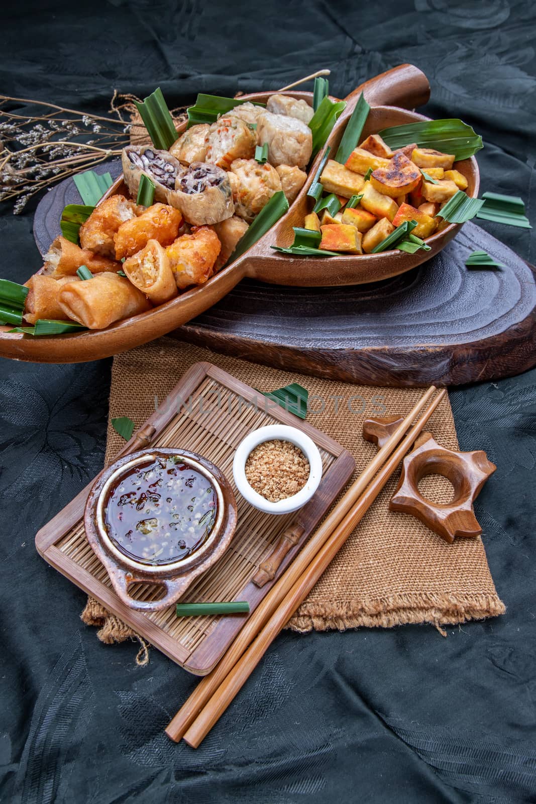 Many vegetarian food : Fried taro rolls (Taro Guangjian) and Deep fried spring rolls, Fried tofu, Fried radish, Fried taro and black beans (Zhu jiao quan or Fried taro cakes) Served with spicy sweet sauce and roasted crushed peanuts with wooden chopsticks on wooden plate. Selective focus.