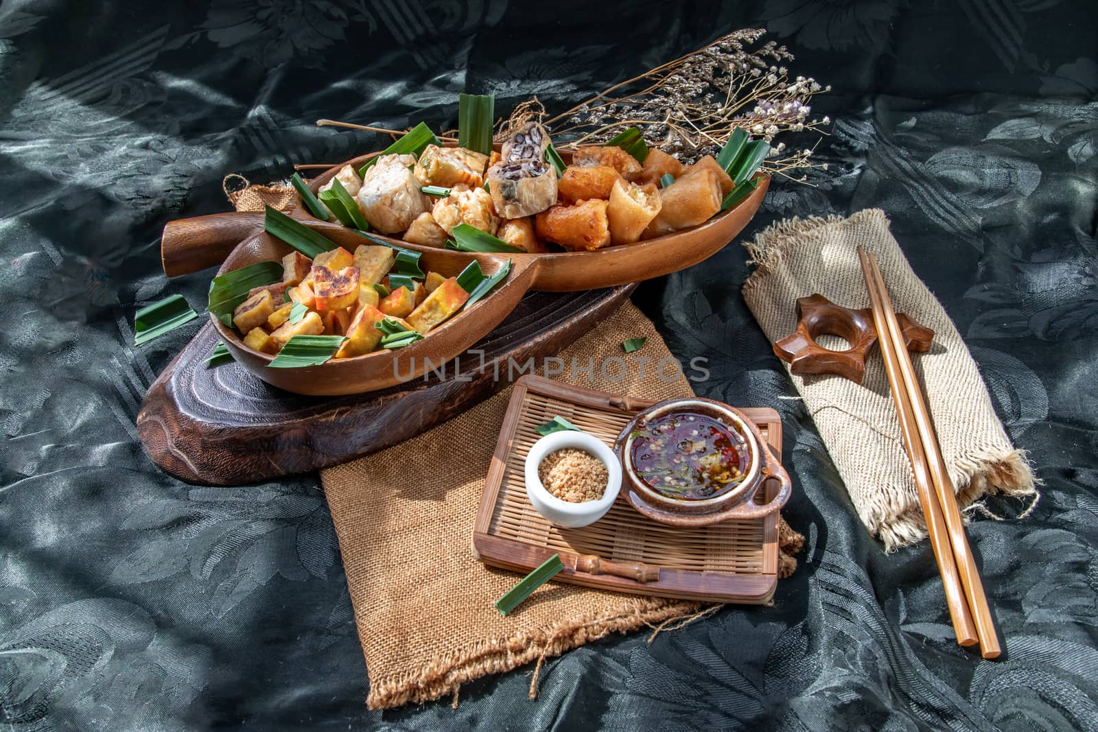 Many vegetarian food : Fried taro rolls (Taro Guangjian) and Deep fried spring rolls, Fried tofu, Fried radish, Fried taro and black beans (Zhu jiao quan or Fried taro cakes) Served with spicy sweet sauce and roasted crushed peanuts with wooden chopsticks on wooden plate. Selective focus.