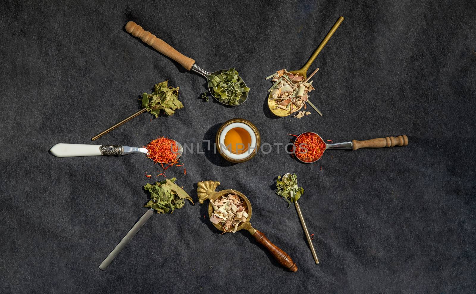 Various teas and dried herbs assortment on spoons in rustic style with honey on balck background. Organic herbal, Selective focus.