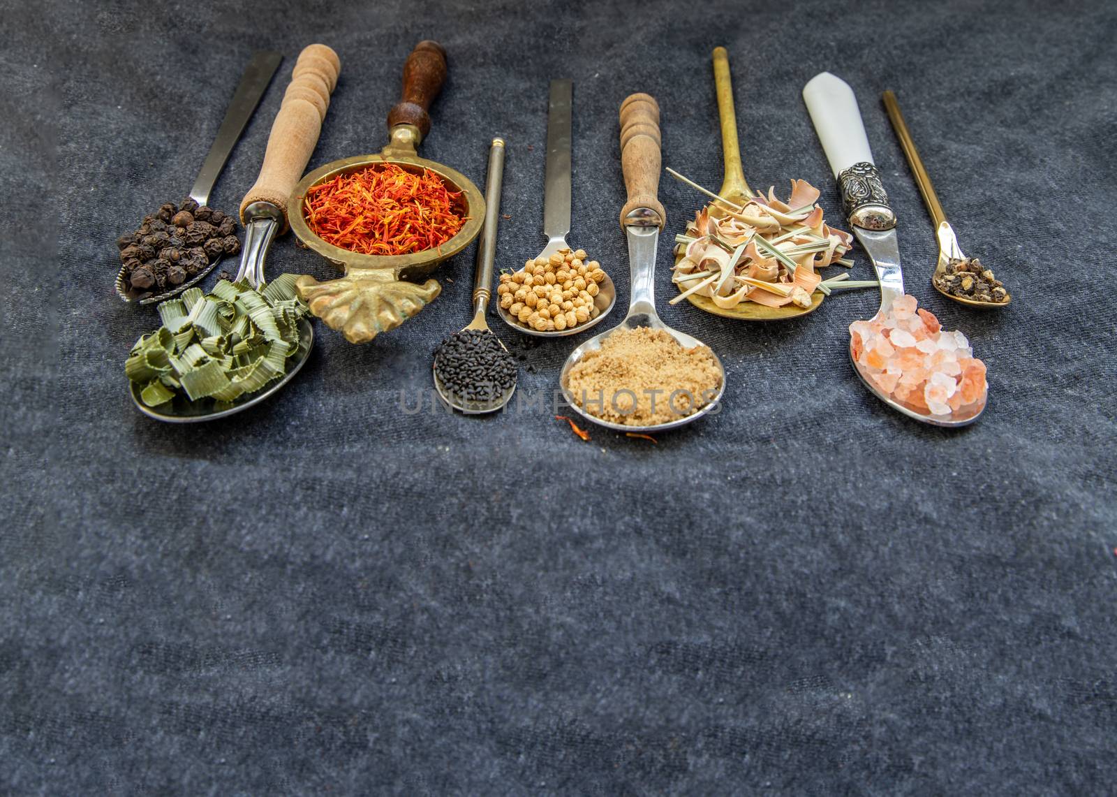 Various teas and dried herbs assortment on spoons in rustic style on balck background. Organic herbal. Selective focus.