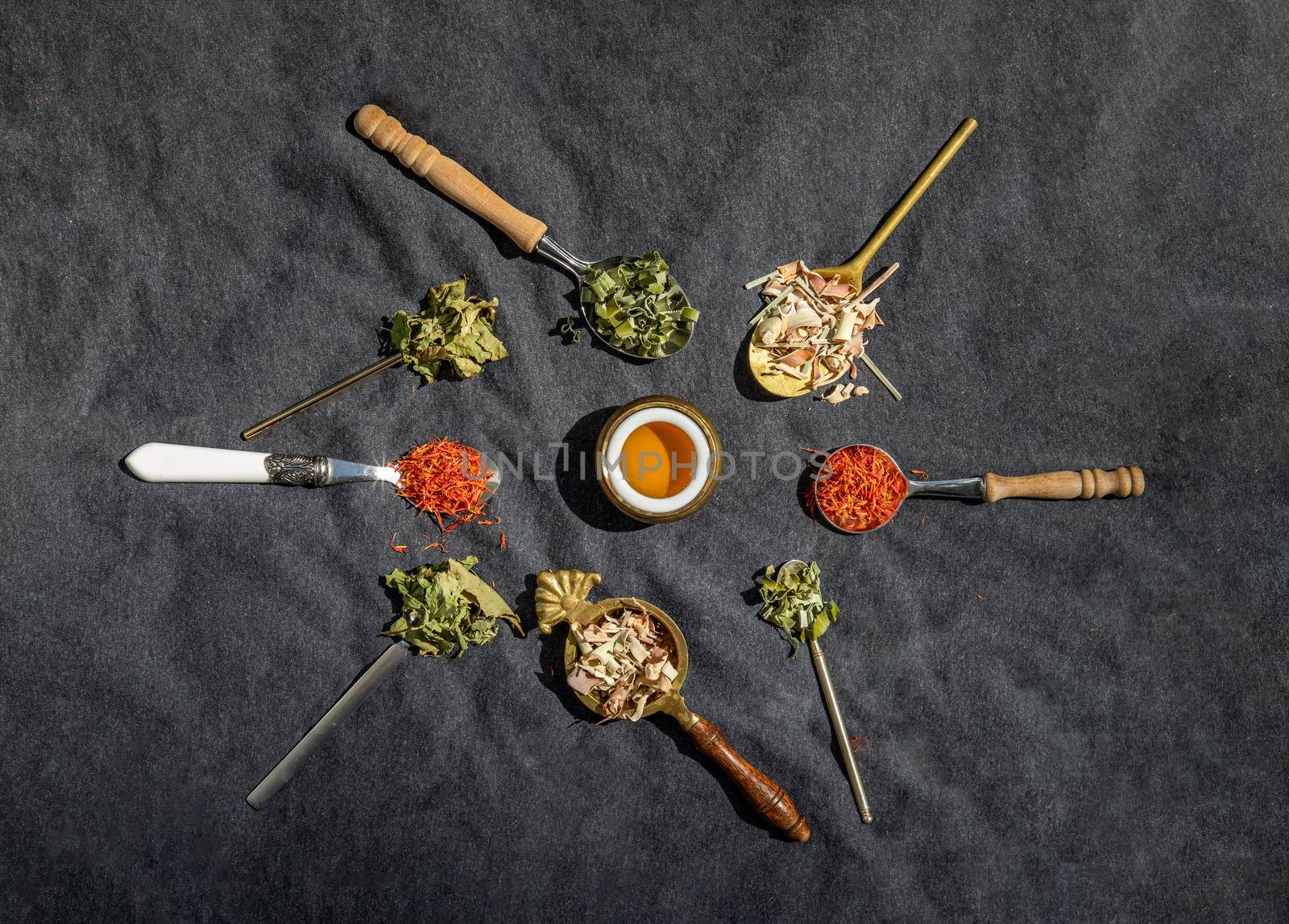 Various teas and dried herbs assortment on spoons in rustic style with honey on balck background. Organic herbal, Selective focus.