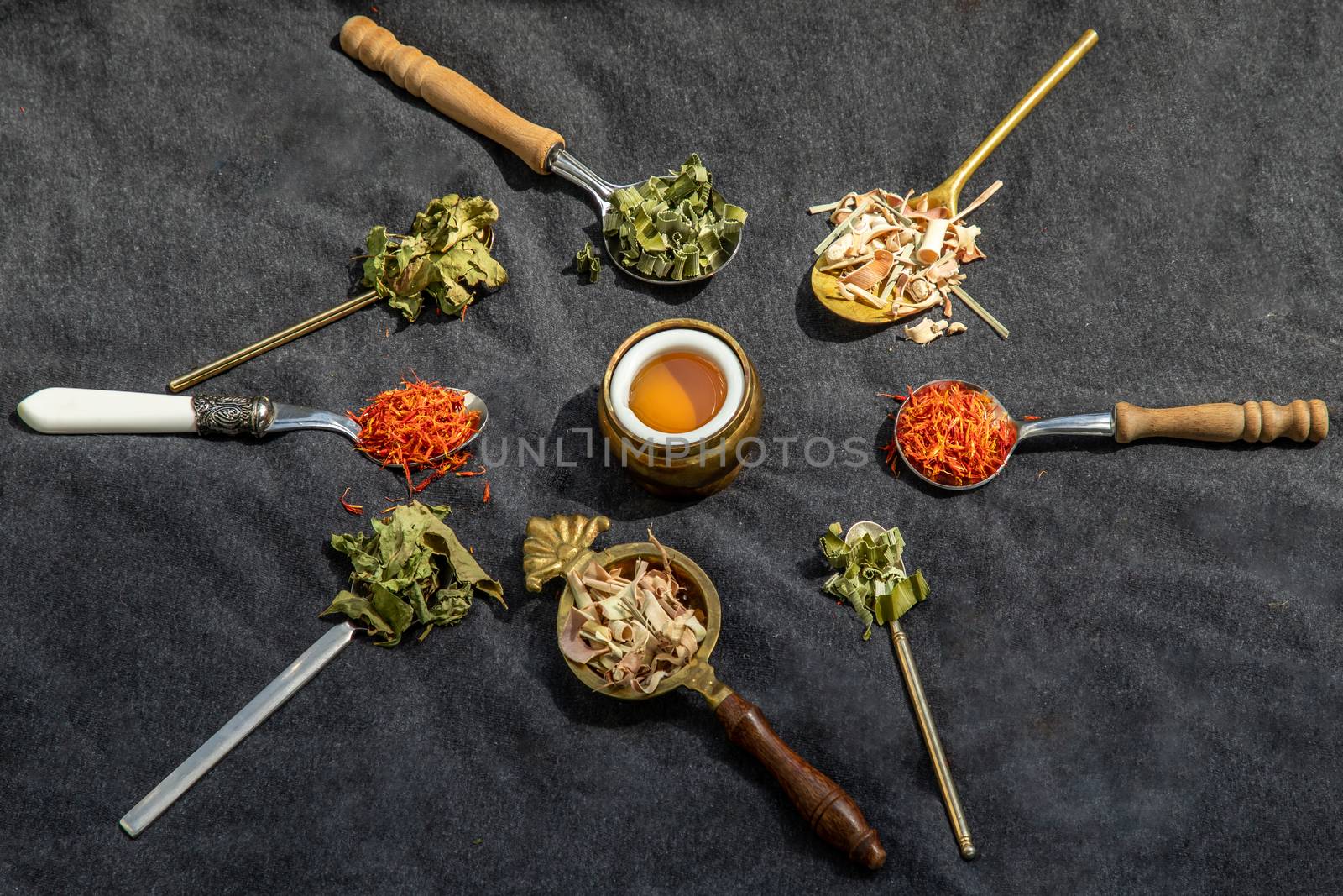 Various teas and dried herbs assortment on spoons in rustic style with honey on balck background. Organic herbal, Selective focus.