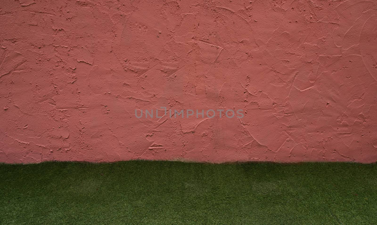 Red-brown cement wall With artificial turf underneath used as background for inserting text.