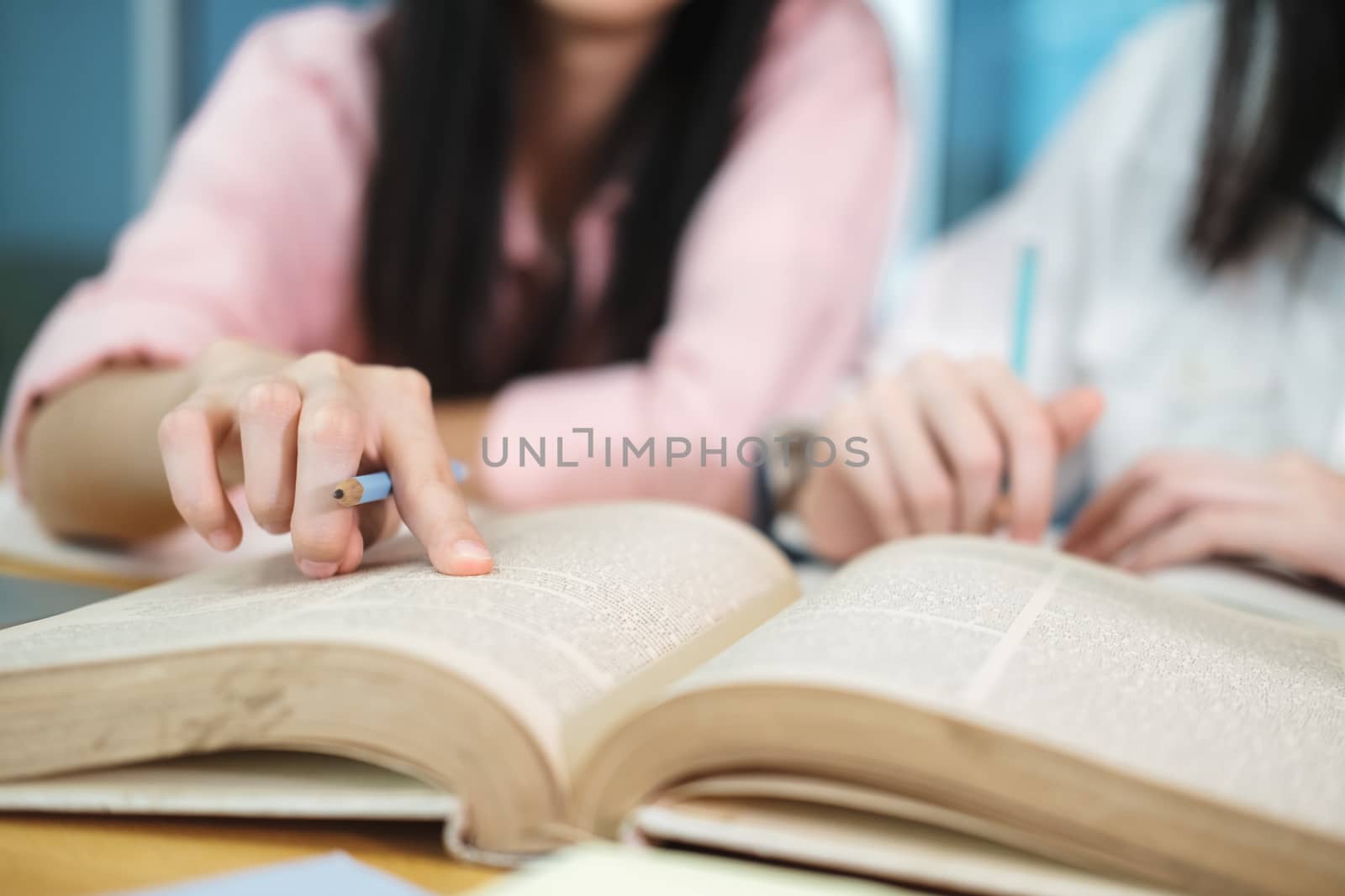 Learning, education and school concept. Young woman and man studying for a test or an exam. Tutor books with friends. Young students campus helps friend catching up and learning.