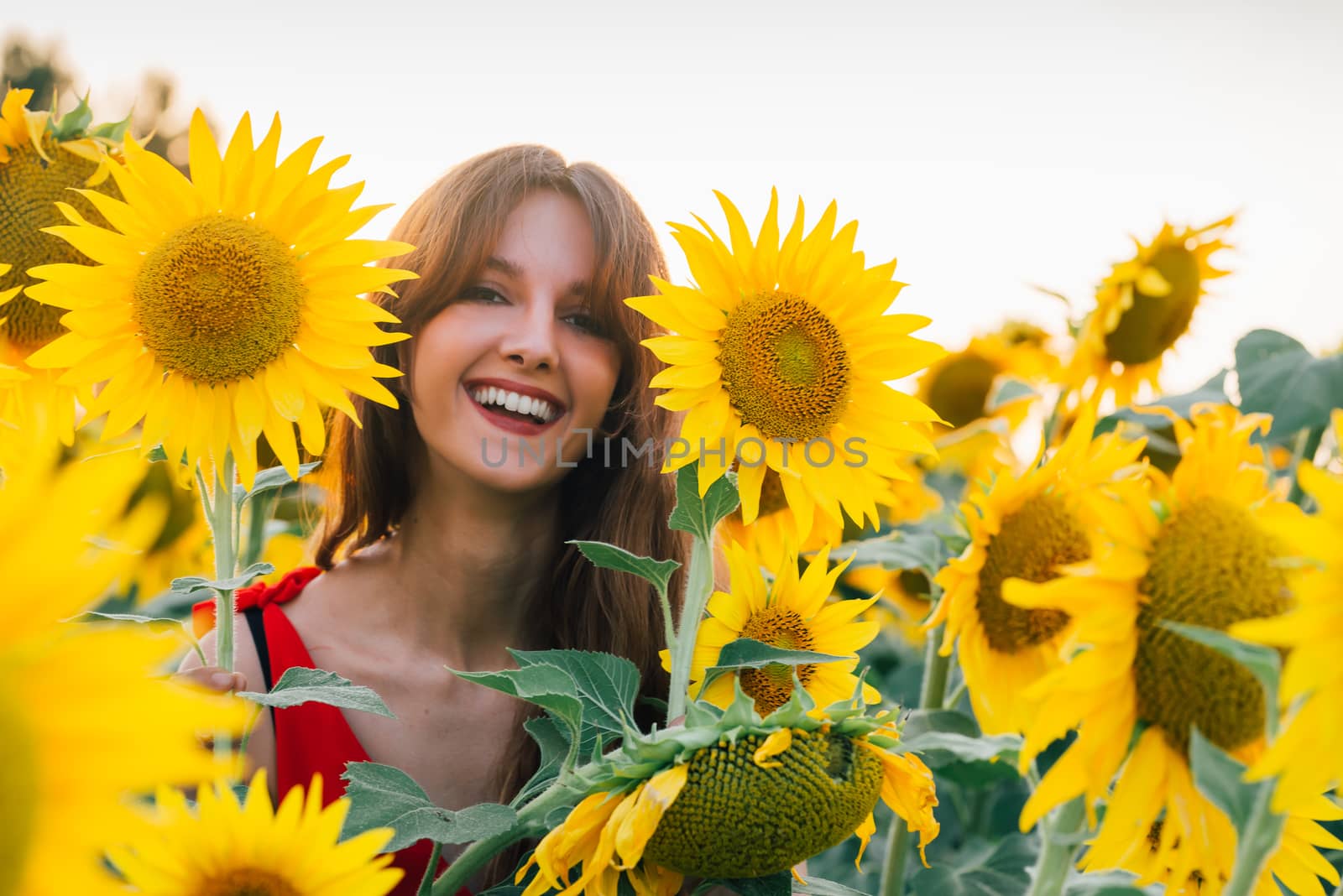 Happy woman with sunflower enjoying nature and laughing on summer sunflower field.