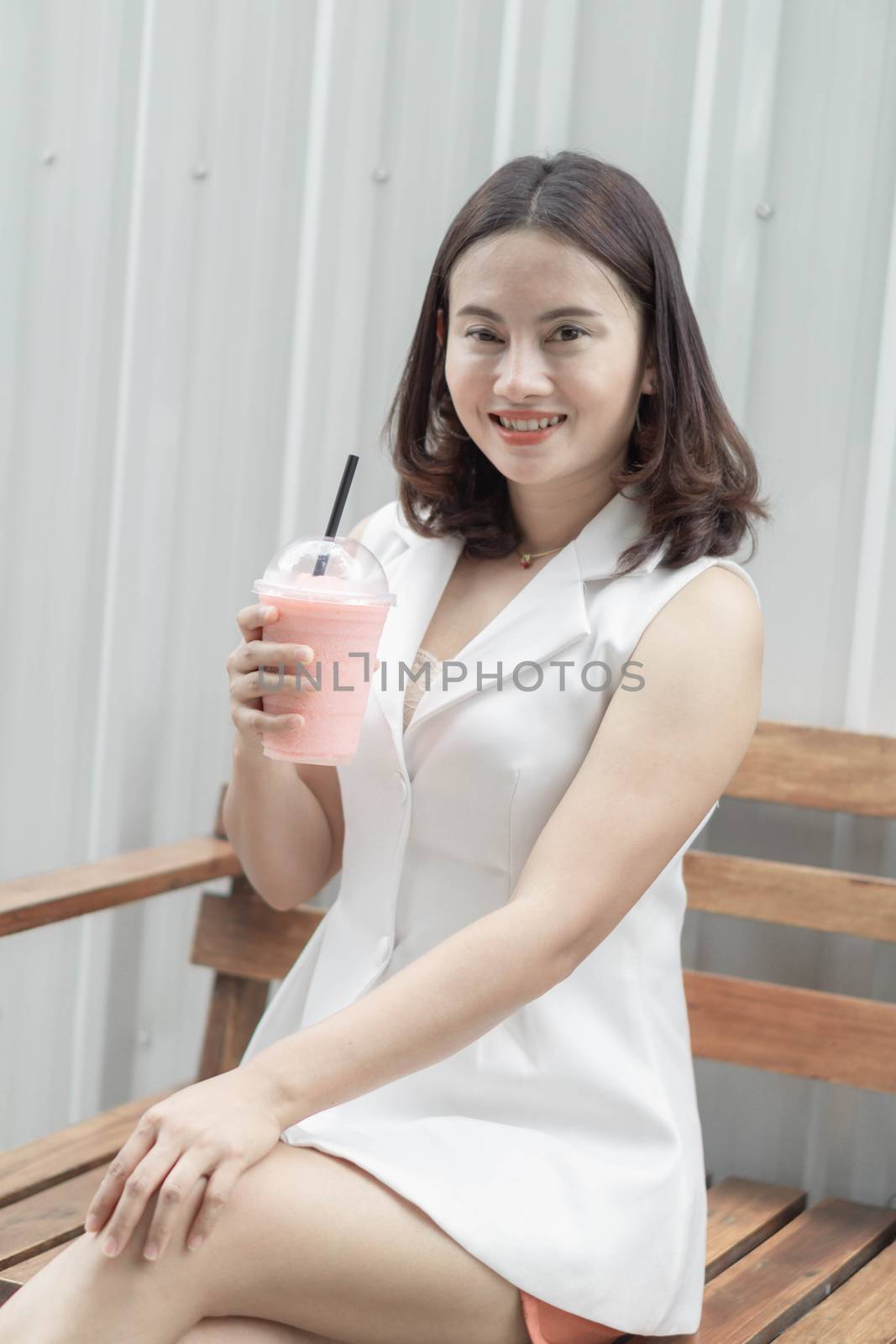 Closeup woman drinking strawberry smoothie and cake with green nature background, selective focus