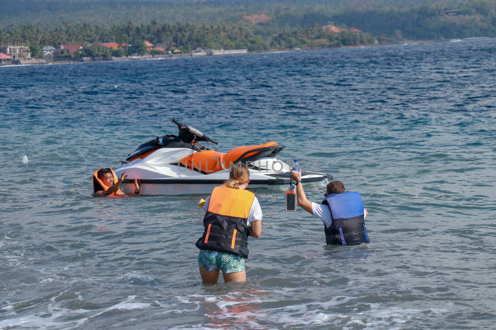 Tourists enjoy driving jet ski on the ocean. A young couple boardes a jetbike by Sanatana2008