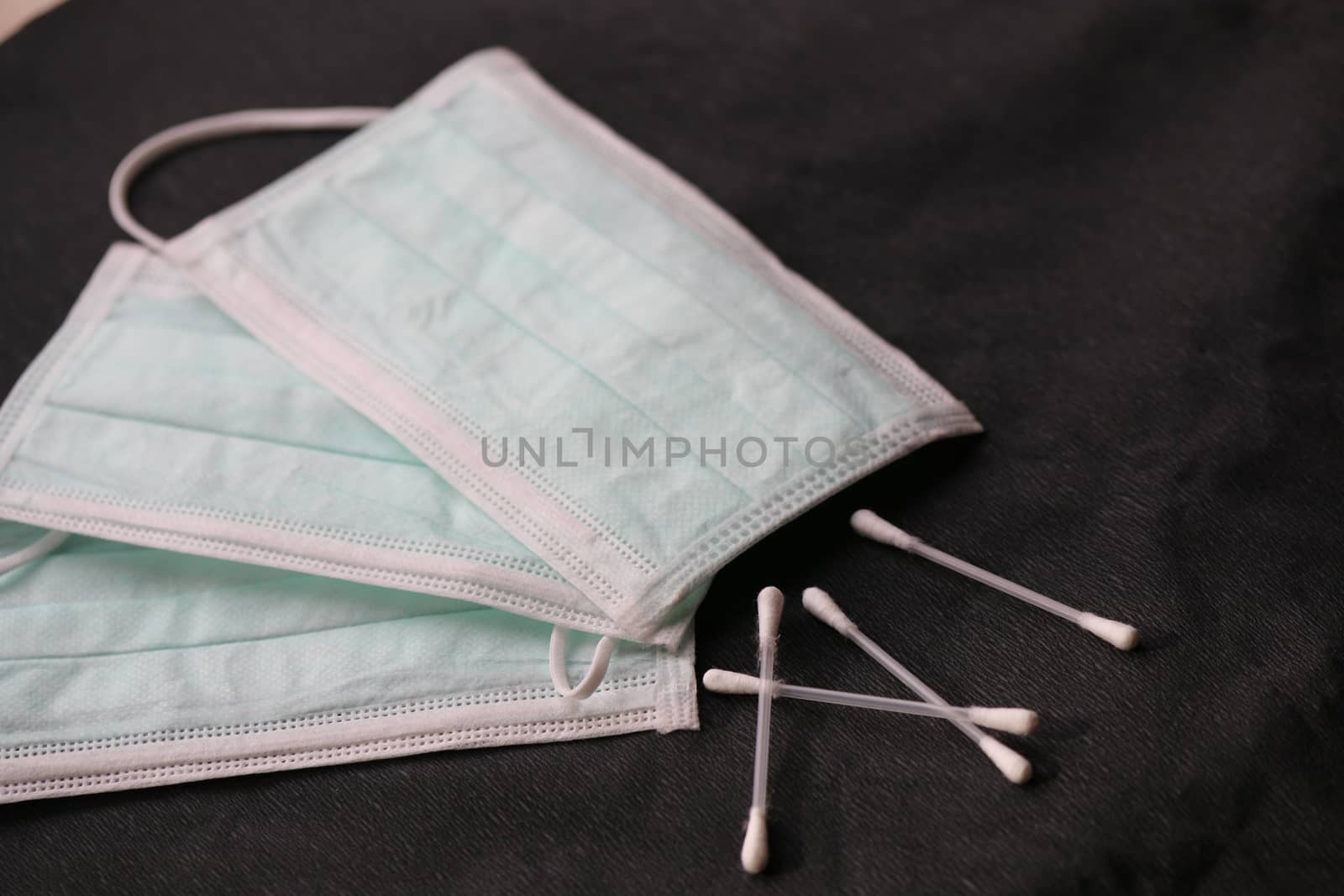 Three Facemasks with cottonbuds on a black surface