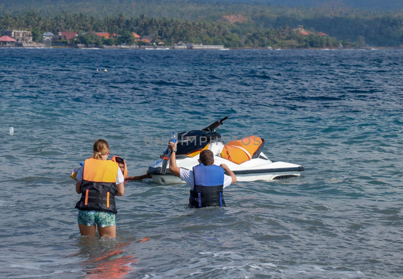 Tourists enjoy driving jet ski on the ocean. A young couple boardes a jetbike by Sanatana2008