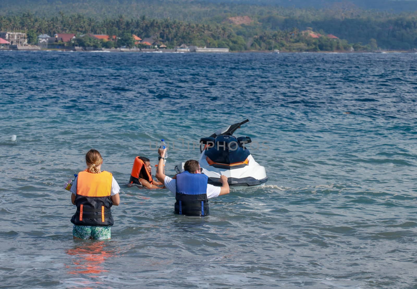 Tourists enjoy driving jet ski on the ocean. A young couple boardes a jetbike by Sanatana2008