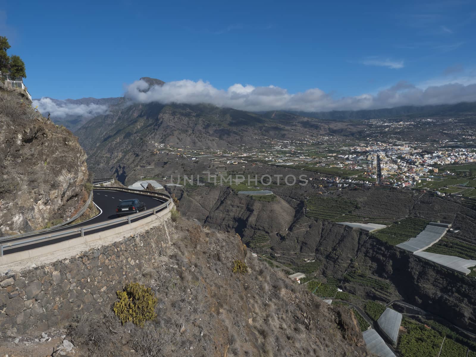 View on car at curved winding asphalt road in steep rocky mountain slope with subtropical volcanic landscape of La Palma, Canary Islands, Spain.