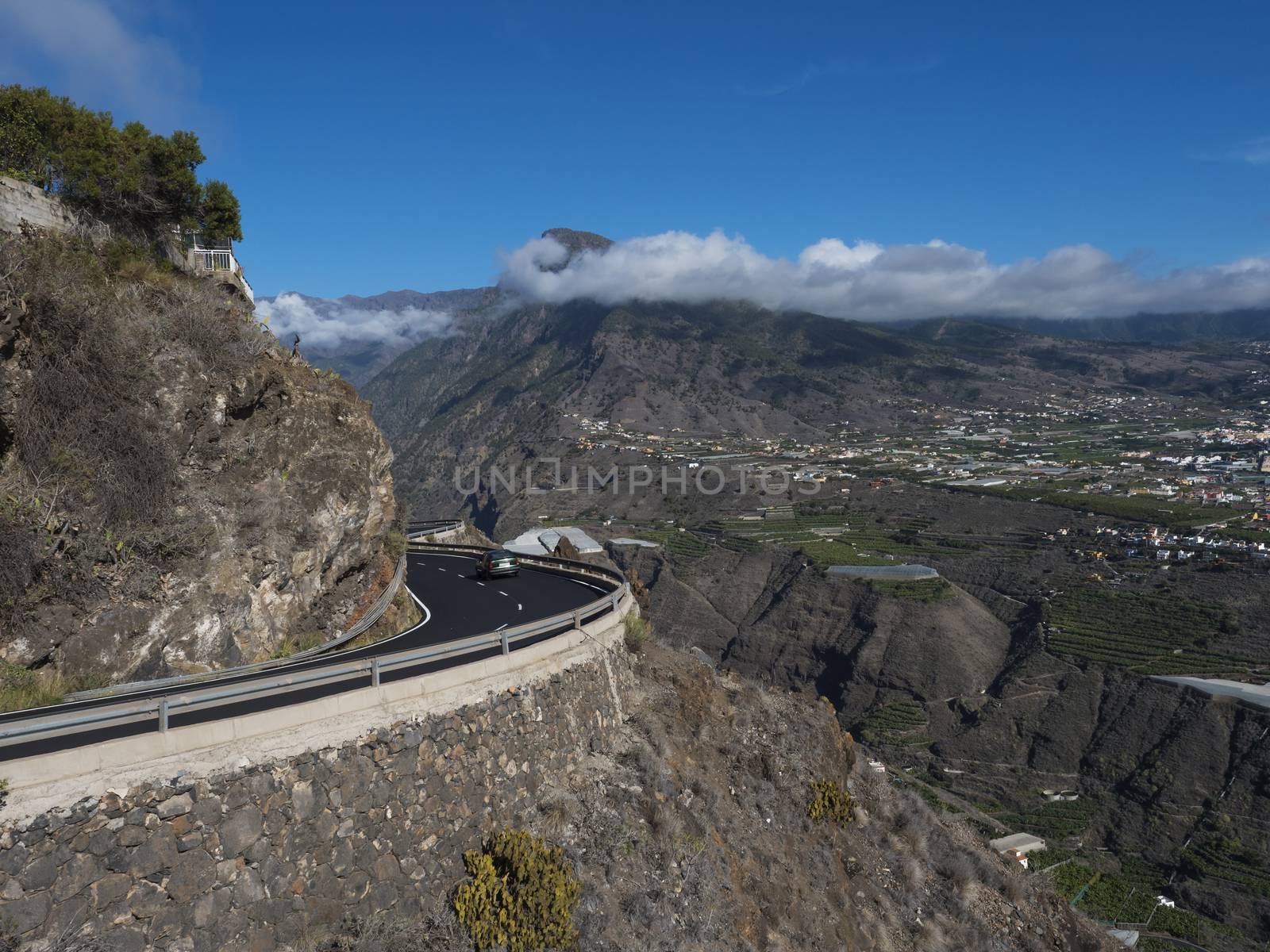 View on car at curved winding asphalt road in steep rocky mountain slope with subtropical volcanic landscape of La Palma, Canary Islands, Spain.