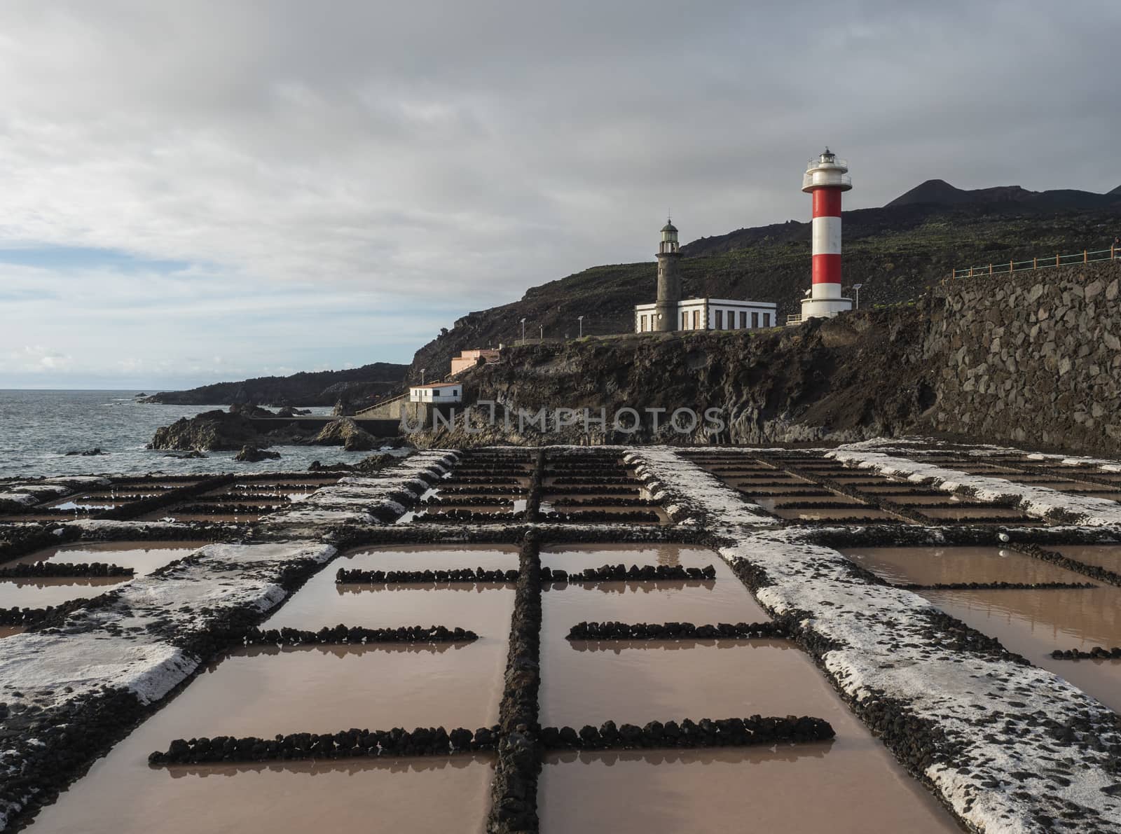 View of Fuencaliente salinas or saltworks and two lighthouse, old stone and white-red striped with volcanic rock field.La Palma, Canary Islands. Ocean, blue sky white clouds