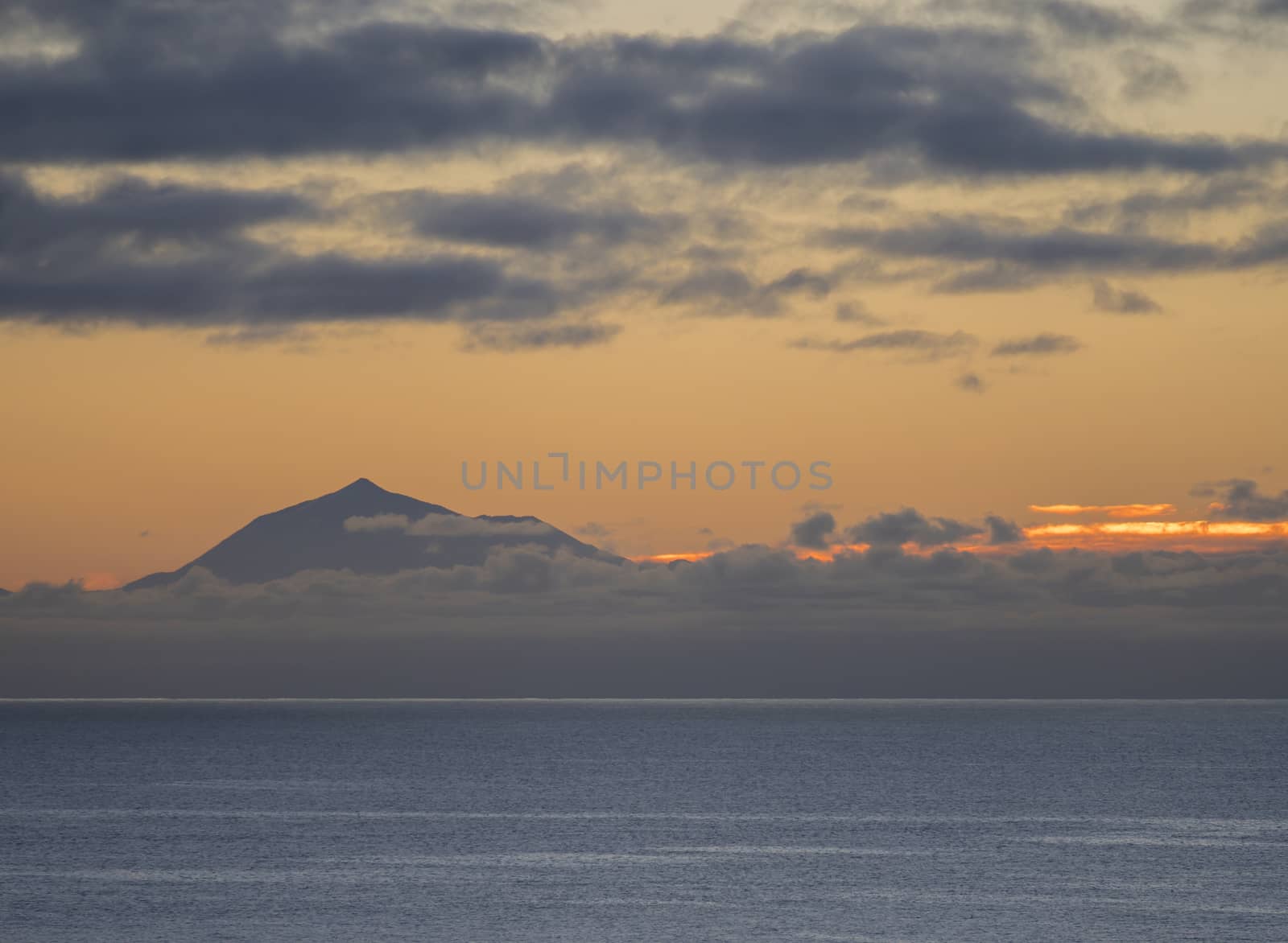 Beautiful orange sunrise over calm ocean and mountain pico del Teide at Tenerife seen from La Palma, Canary Island.