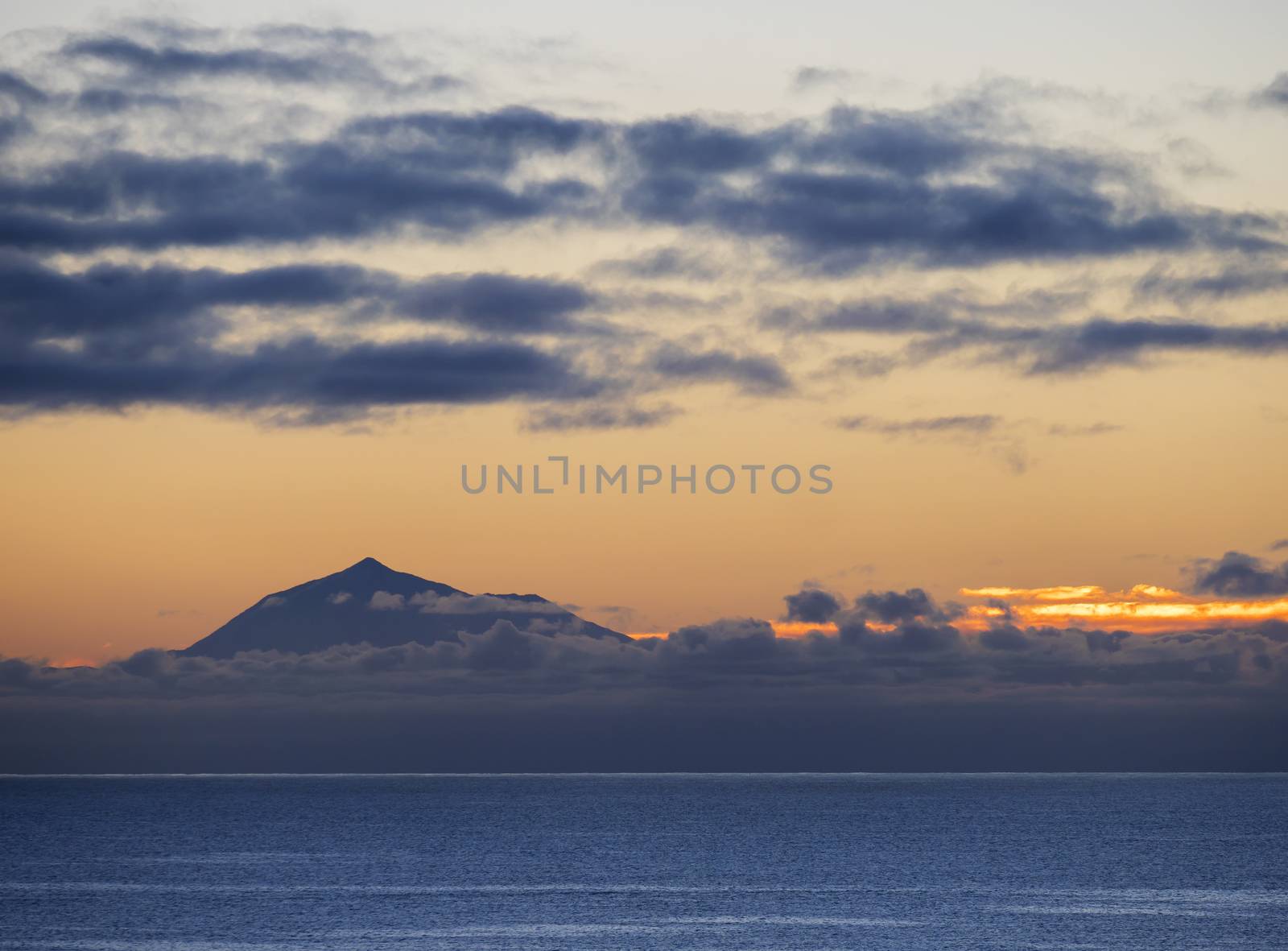Beautiful orange sunrise over calm ocean and mountain pico del Teide at Tenerife seen from La Palma, Canary Island.