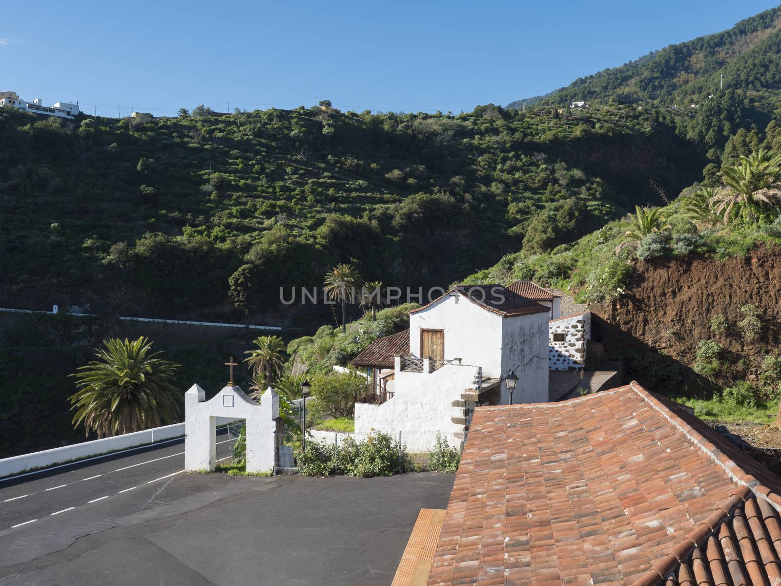 Old traditional houses at village Las Nieves with green mountains and subtropical vegetation, blue sky background. La Palma, Canary Islands