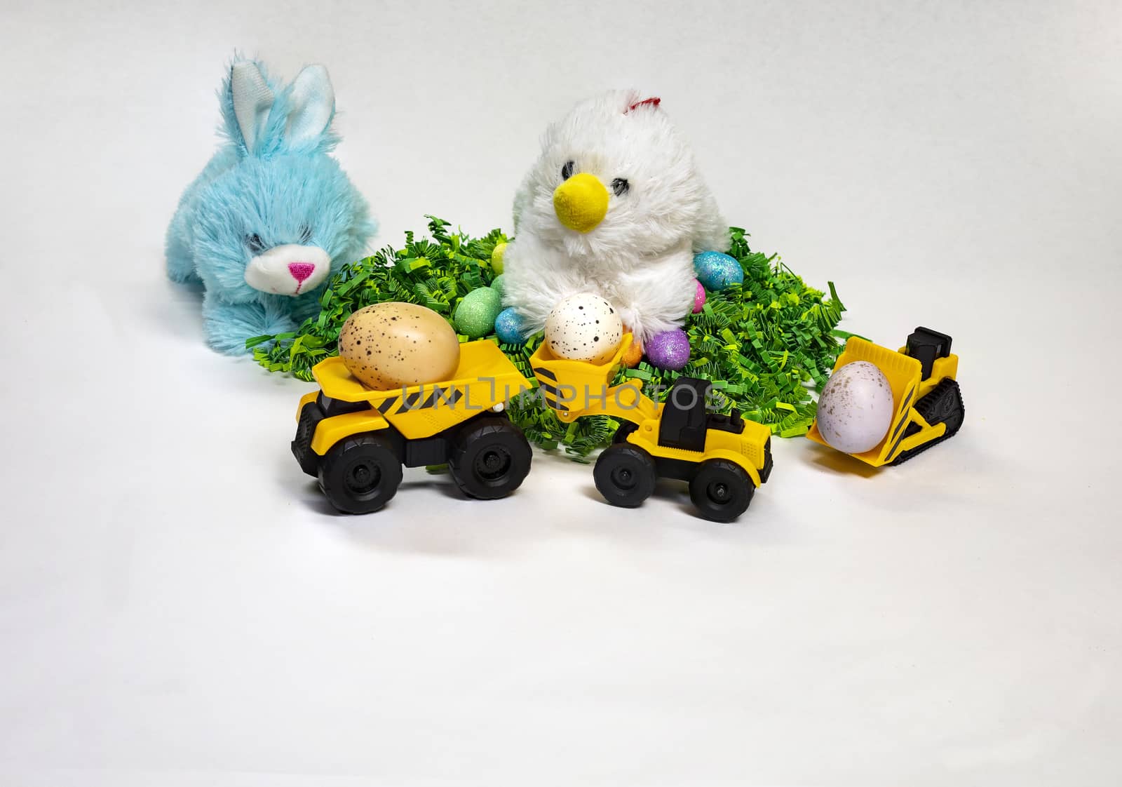 Easter themed photo of stufed bunny and hen with decorated Easter eggs and a child's toy construction vehicles.