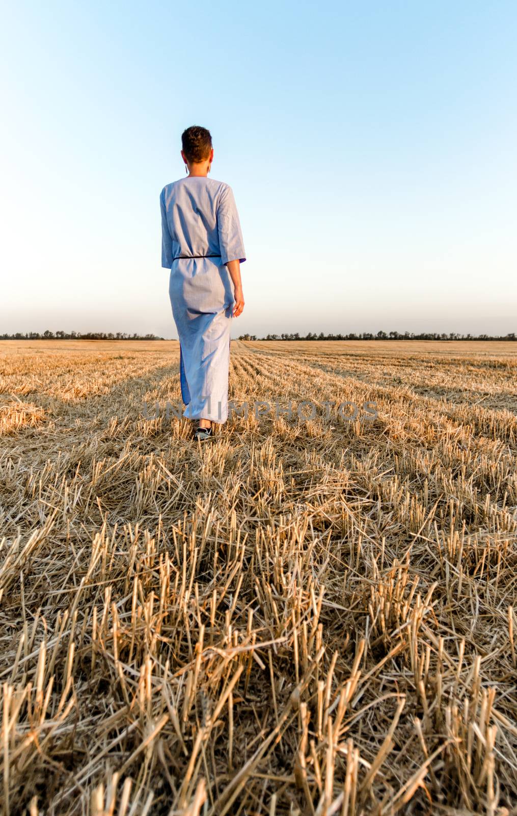 woman farmer walks through a mown wheat field in Ukraine by Gera8th