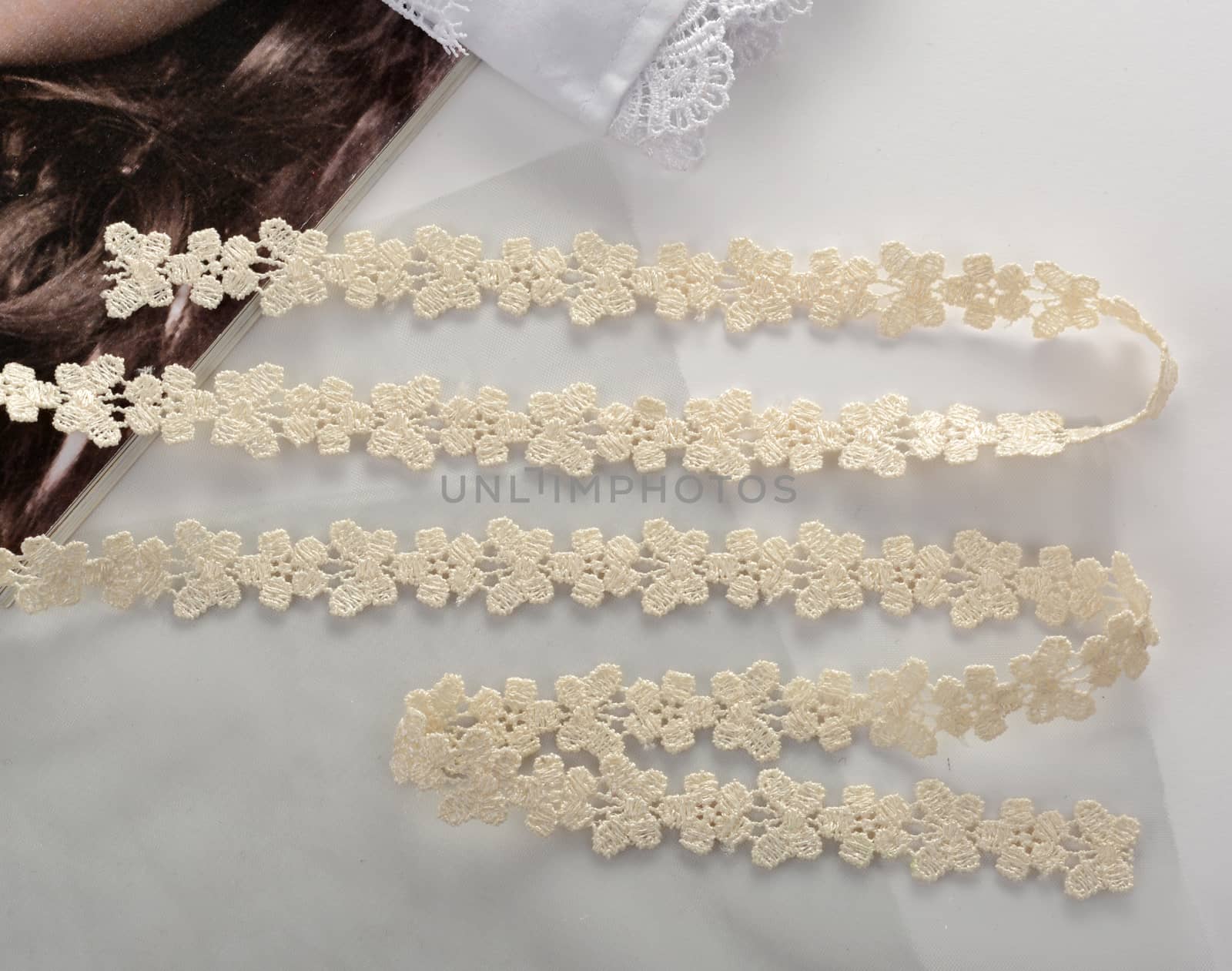 Tapes of beige gentle guipure, beauty lace fabric on light background. Elastic material. Using for Atelier and needlework store.