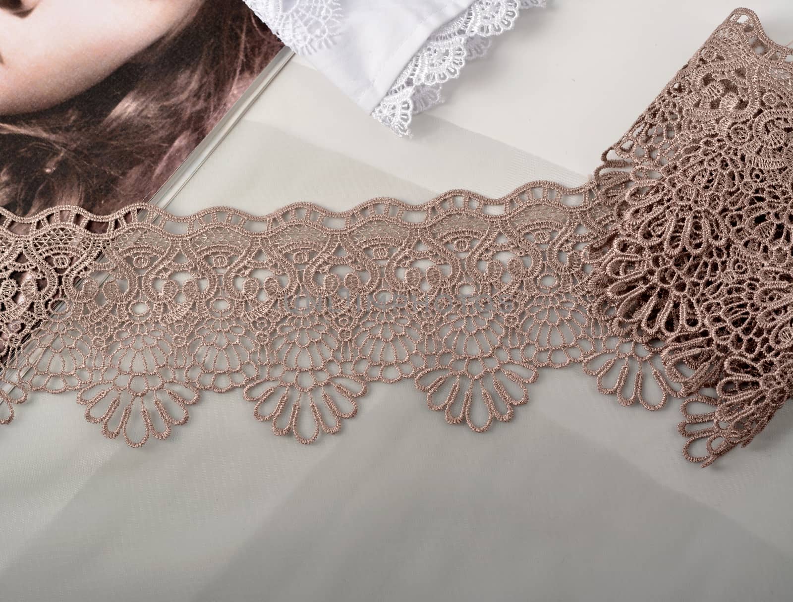 Tapes of beige gentle guipure, beauty lace fabric on light background. Elastic material. Using for Atelier and needlework store.