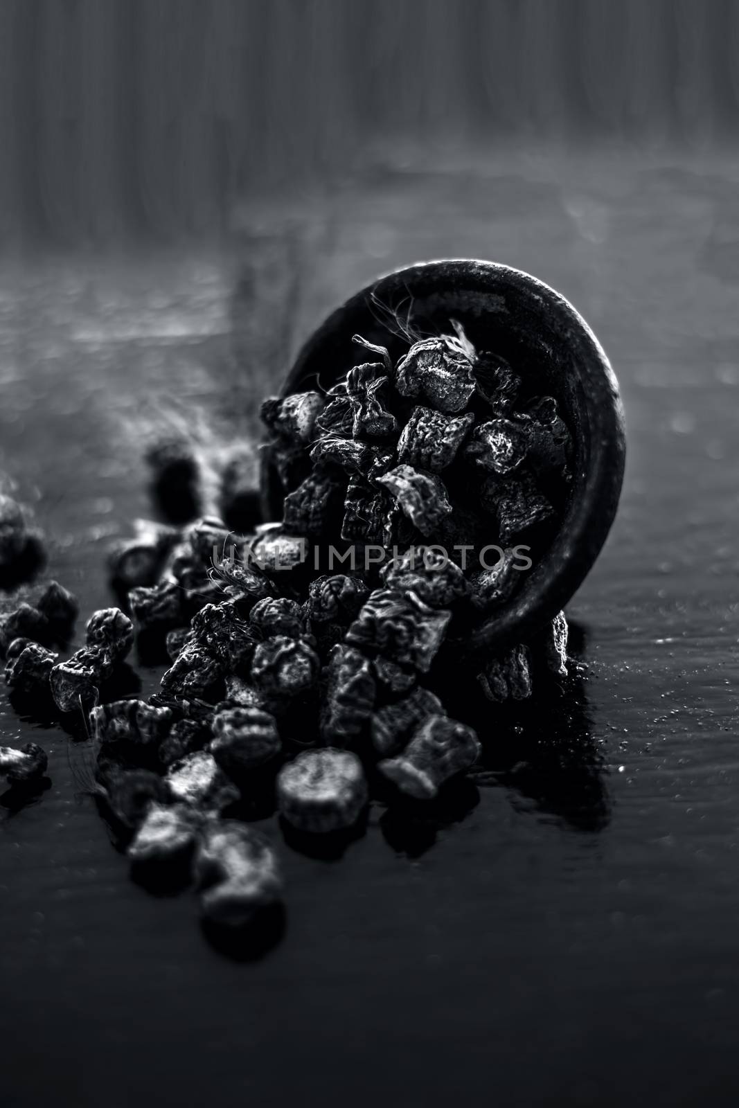 Popular Indian &amp; Asian ayurvedic organic herb musli or Chlorophytum borivilianum or Curculigo orchioides or kali moosli in a clay on wooden surface.