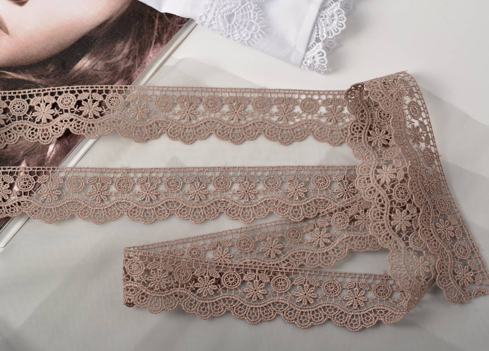 Tapes of beige gentle guipure, beauty lace fabric on light background. Elastic material. Using for Atelier and needlework store.