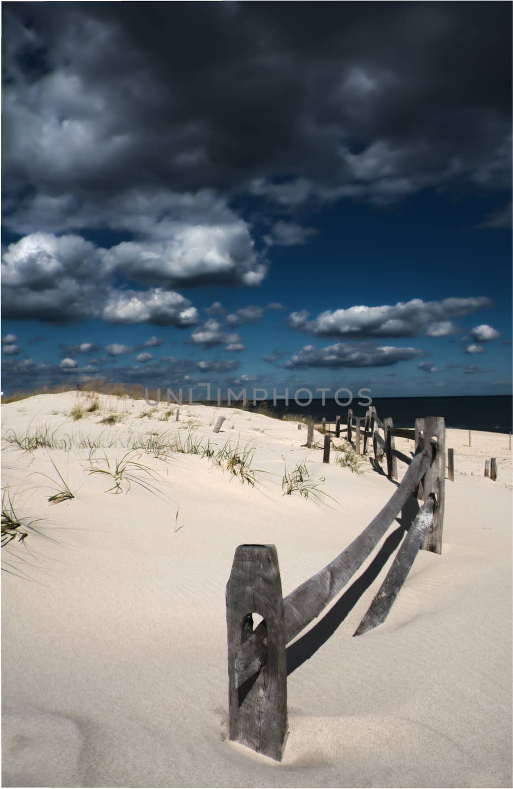White sand shoreline. Wooden fence.