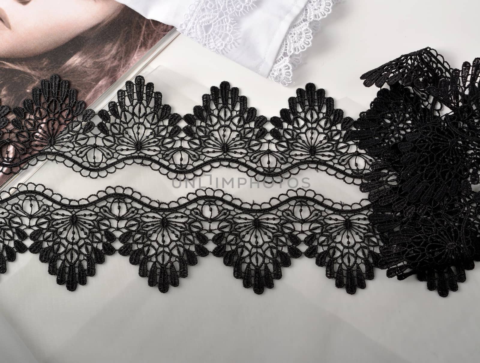 Tapes of black gentle guipure, beauty lace fabric on light background. Elastic material. Using for Atelier and needlework store.