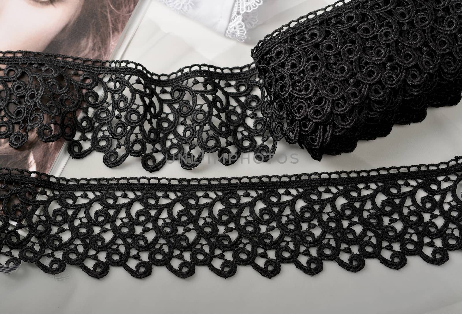 Tapes of black gentle guipure, beauty lace fabric on light background. Elastic material. Using for Atelier and needlework store.
